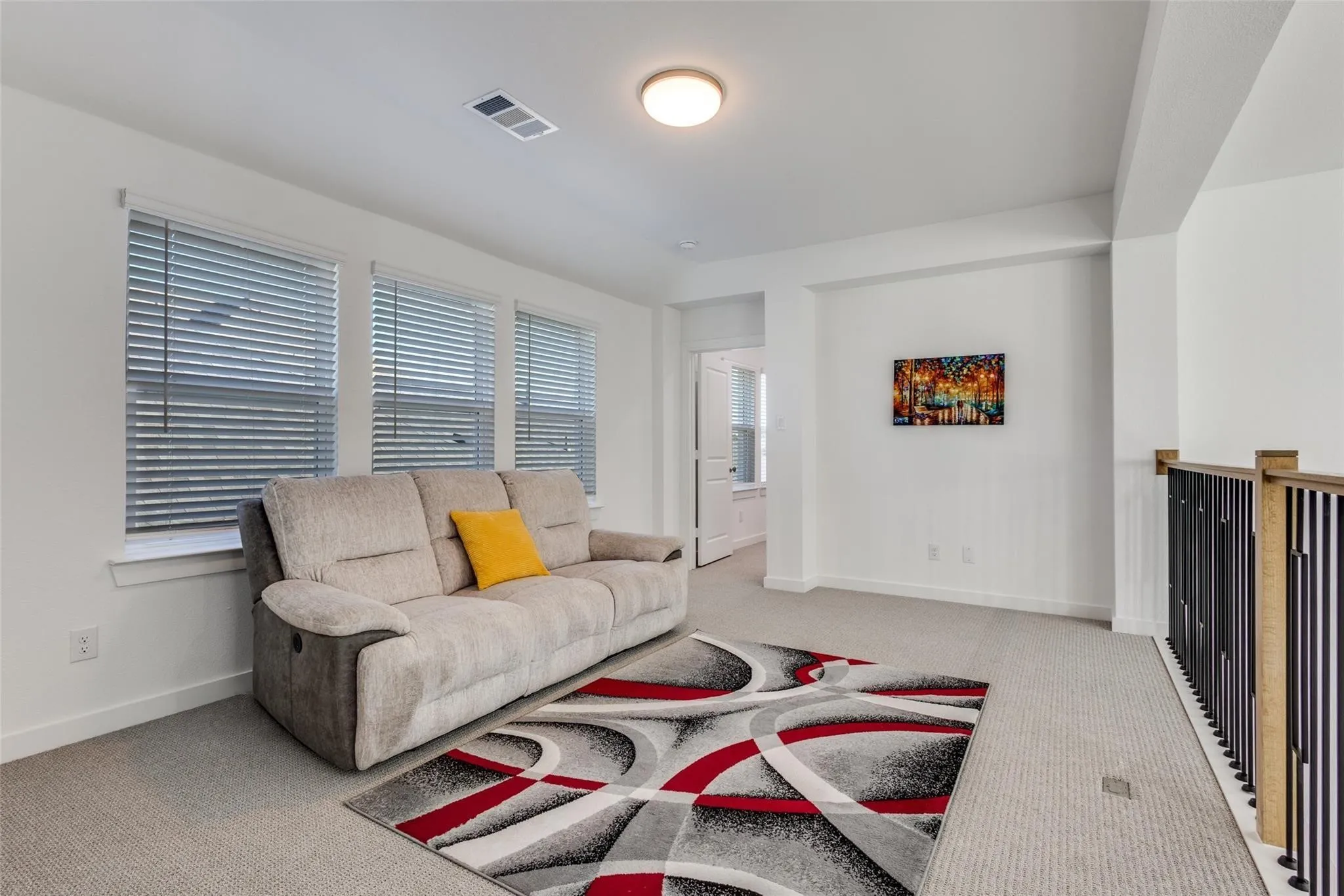 Carpeted lounge space with multiple windows, recessed lighting, and a contemporary wood and metal railing