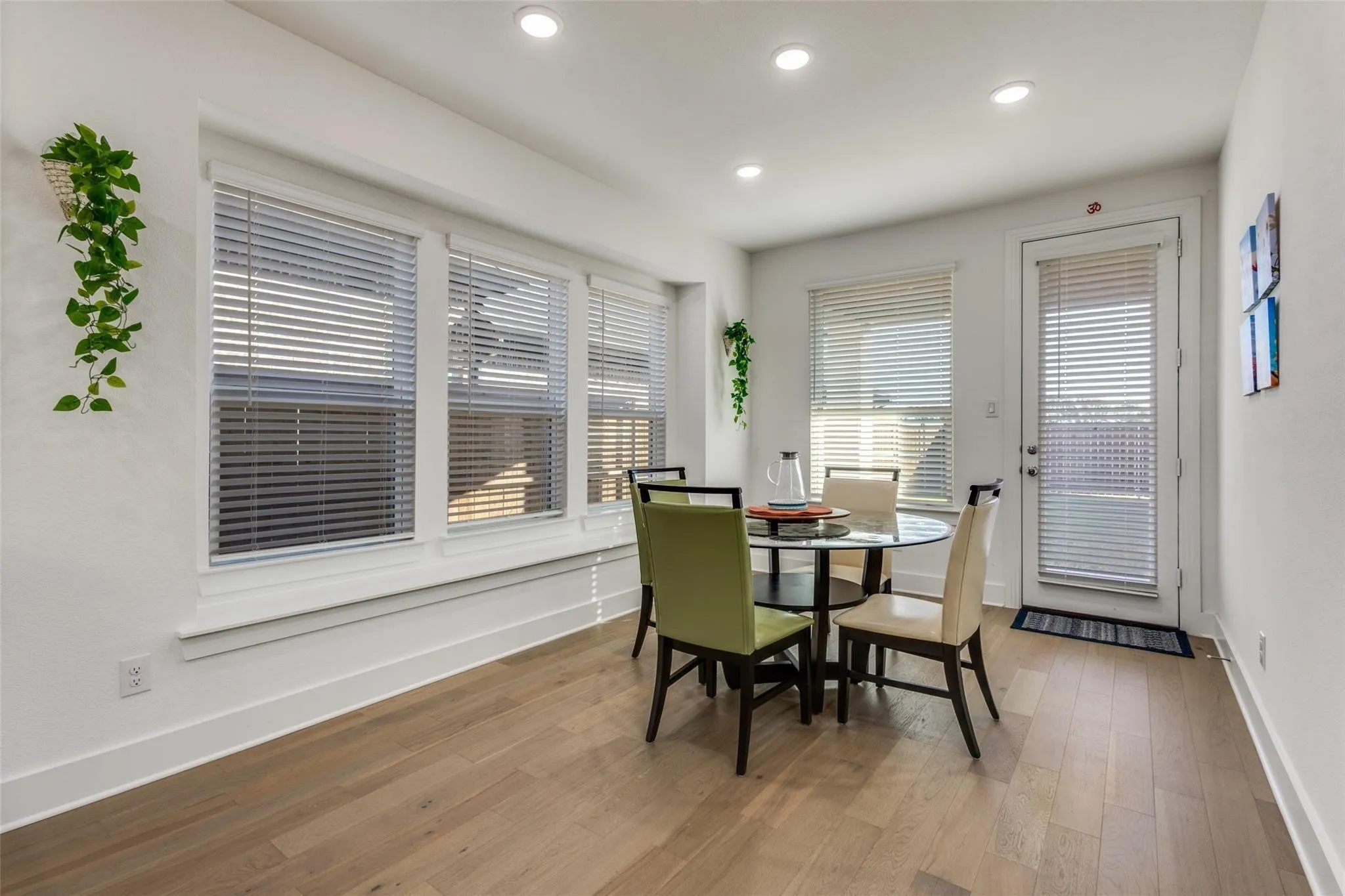 Recessed lighting, light wood-finish flooring, multiple windows with blinds, white trim, and a white door with blinds