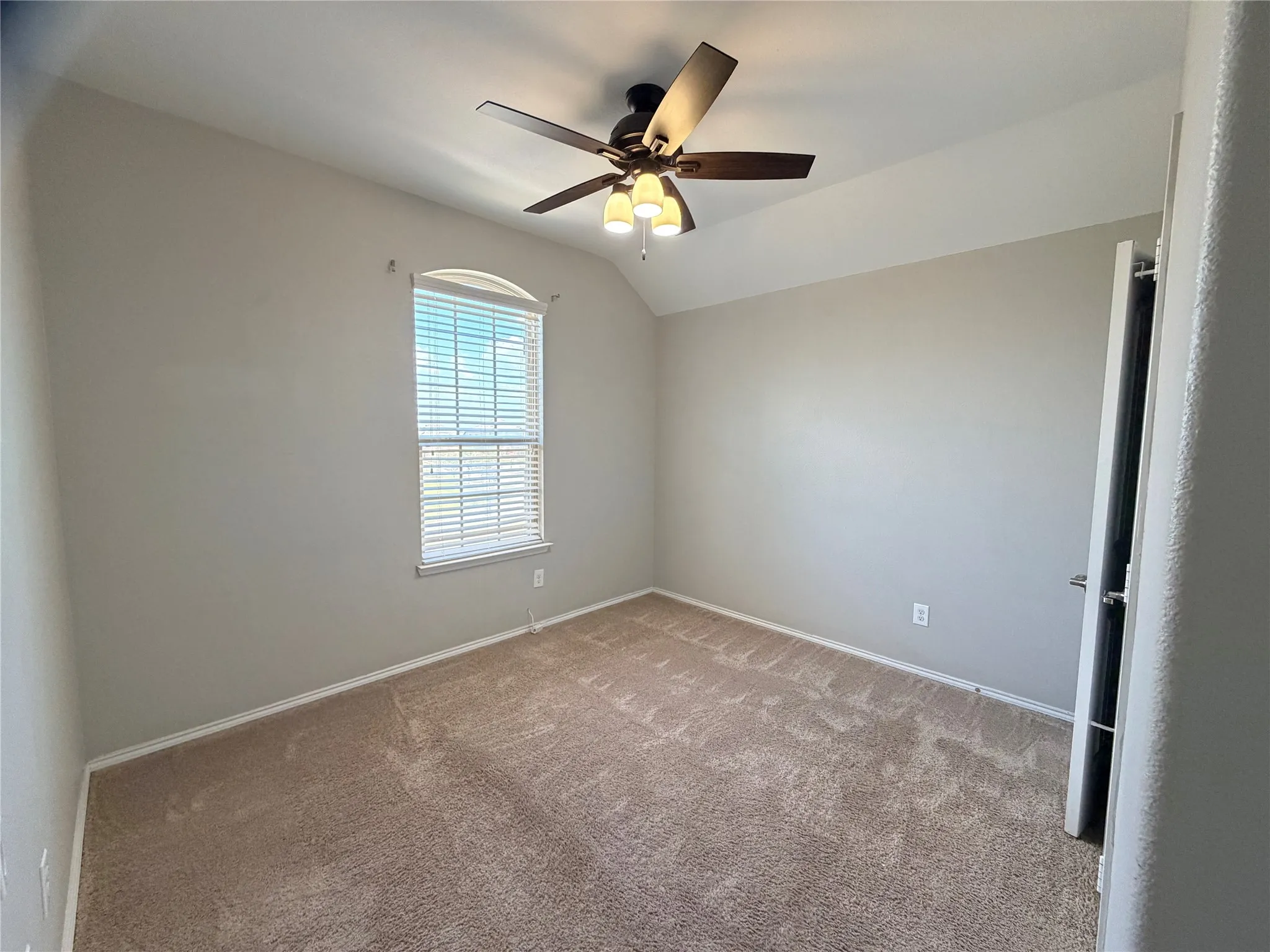 Arched window with blinds, ceiling fan with integrated lighting, neutral wall paint, and carpet flooring