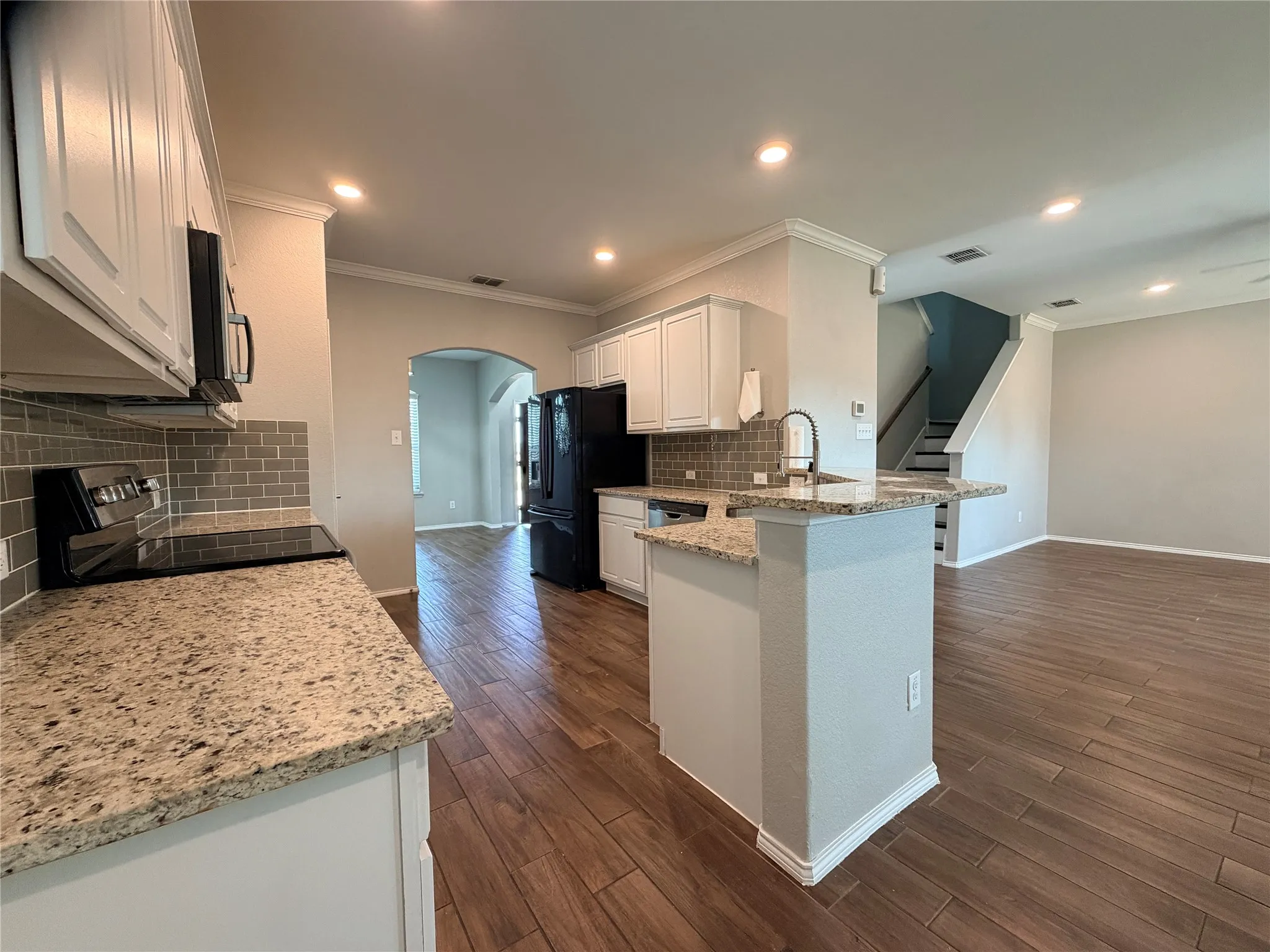 Kitchen featuring white cabinetry, granite countertops, tile backsplash, built-in appliances, and wood-finish flooring