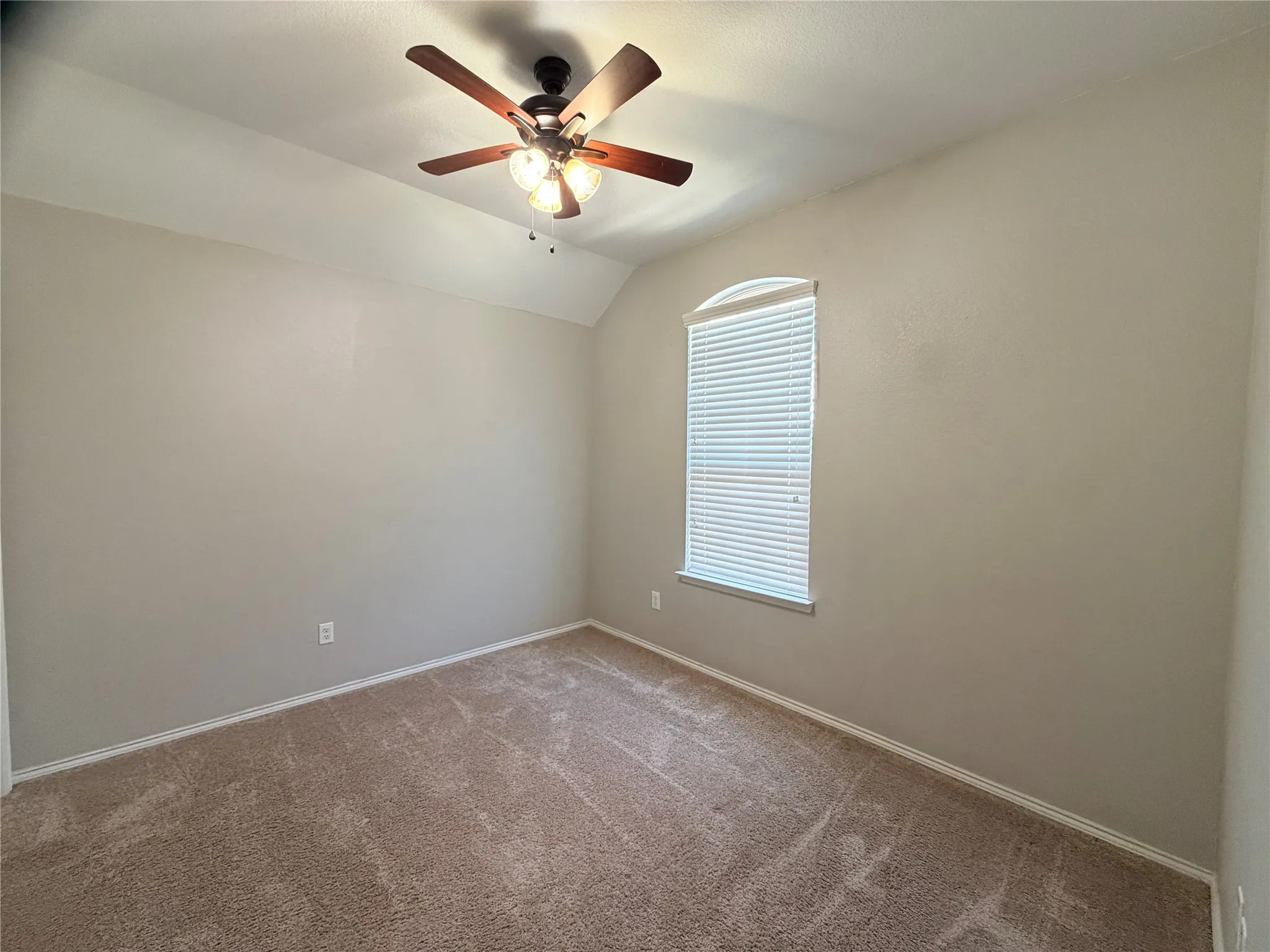Vaulted ceiling with a ceiling fan, arched window, and neutral wall paint