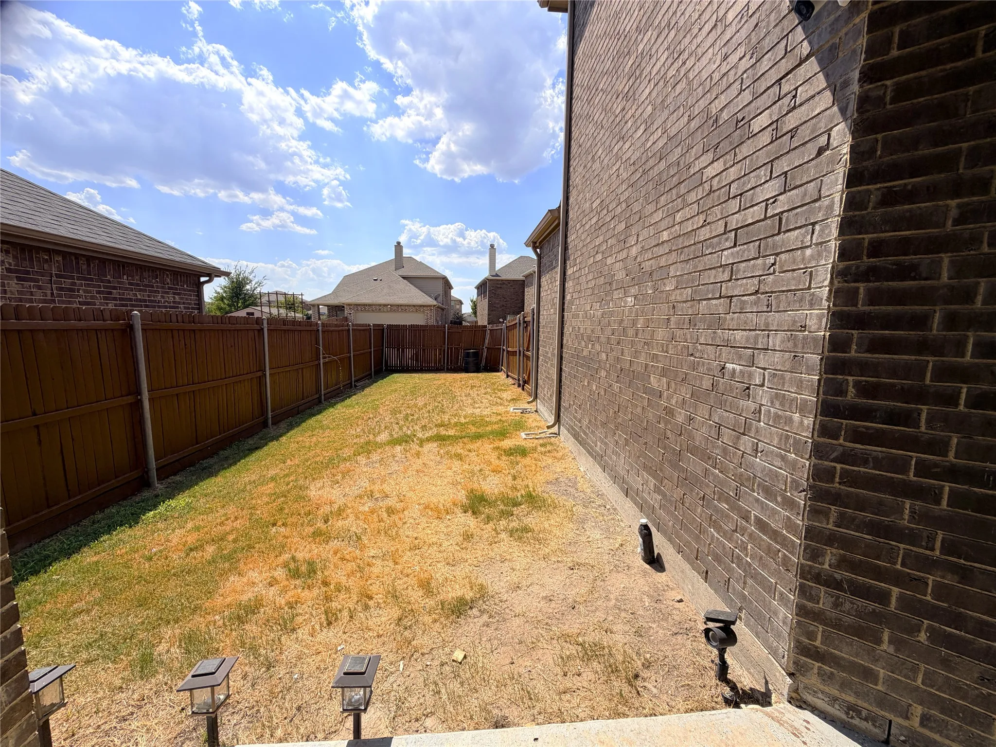 Brick exterior, wood privacy fence, and concrete patio