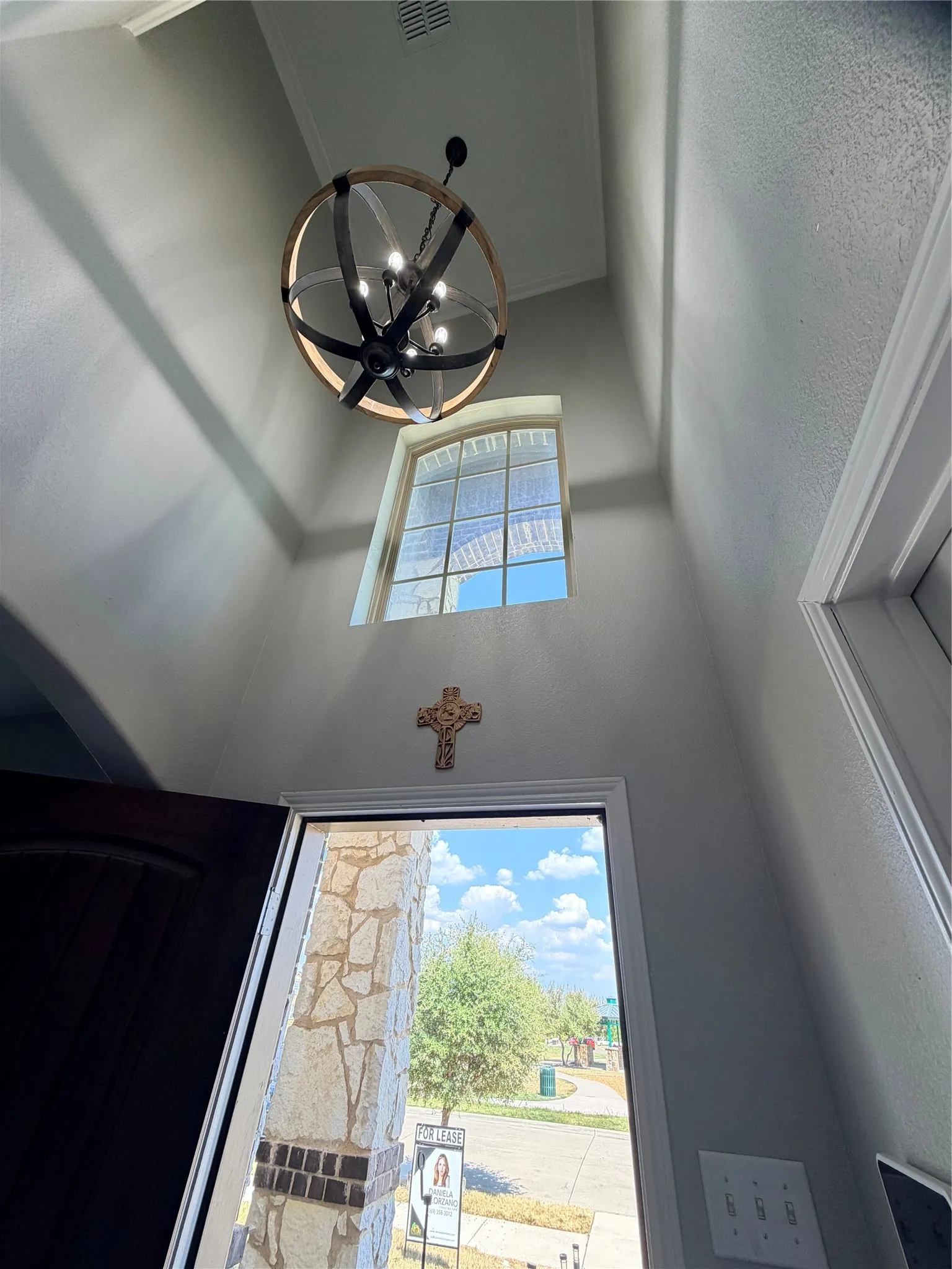 Front door. Vaulted ceiling with an architectural light fixture and an arched window