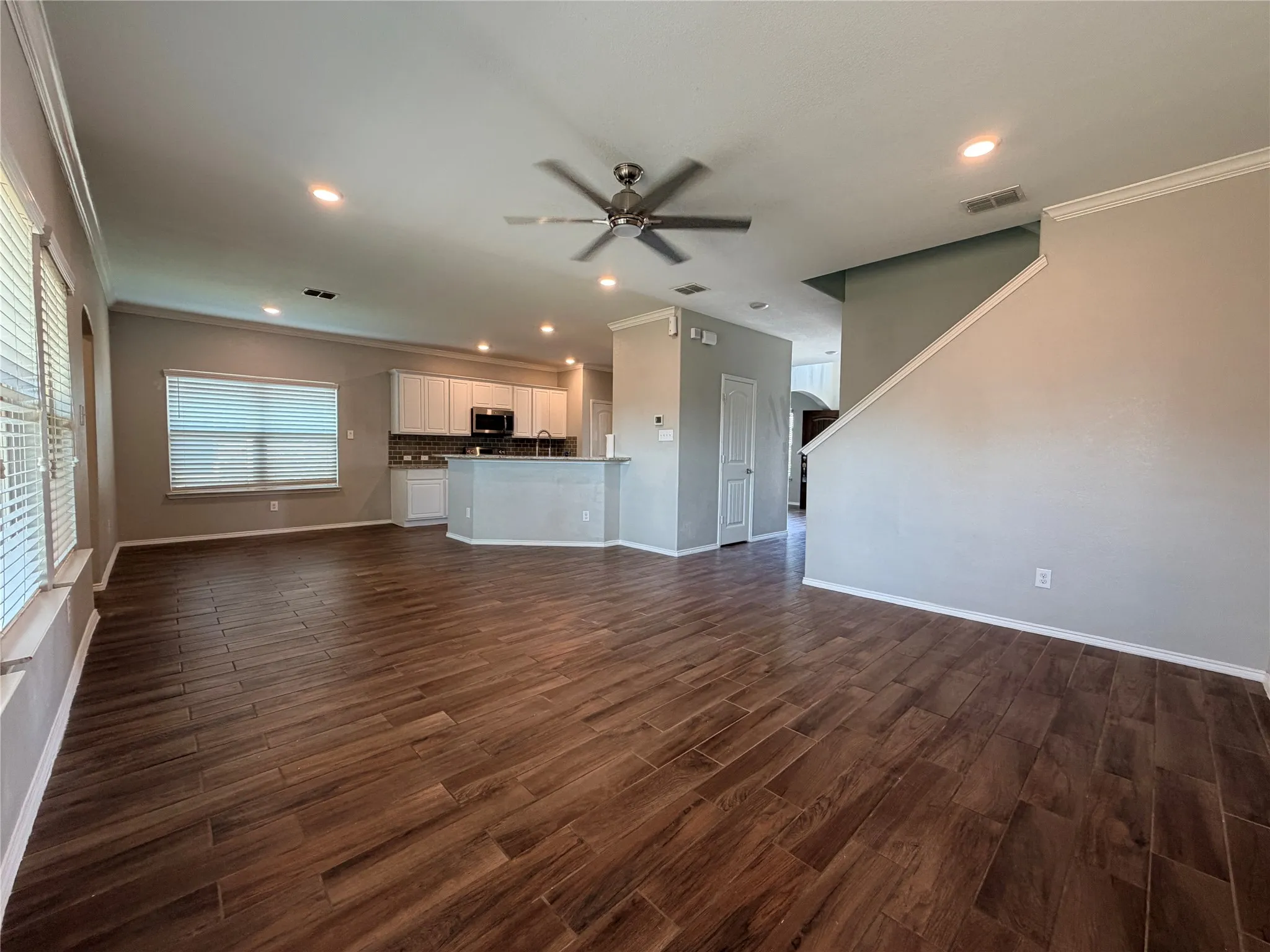 Expansive open-concept space featuring wood-finish flooring, recessed lighting, and a ceiling fan