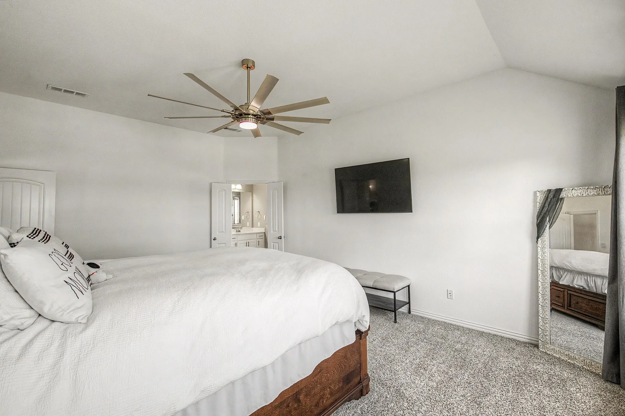 Vaulted ceiling with an overhead fan, carpeted flooring, and a wall-mounted flat-screen display