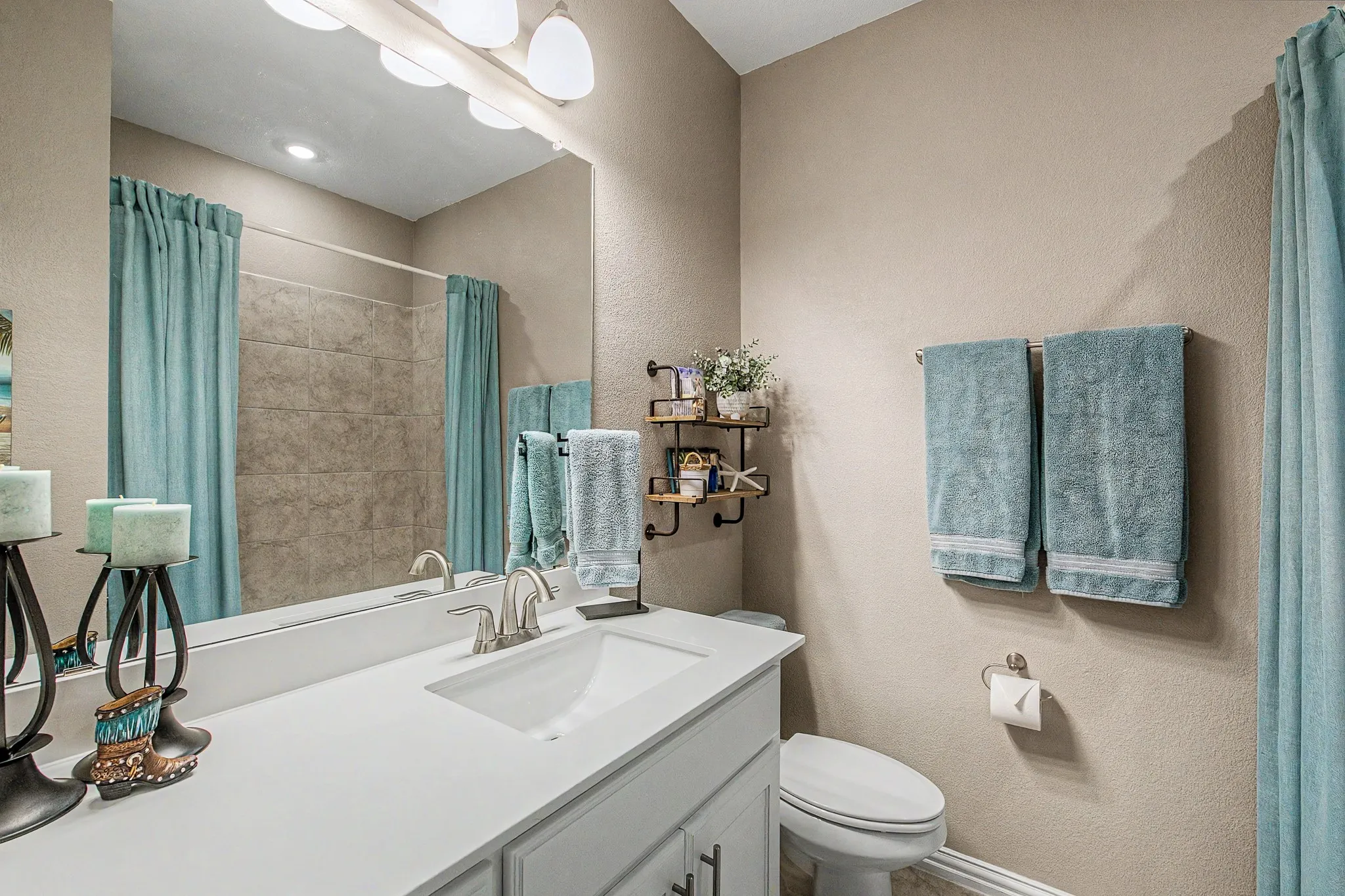 Vanity with integrated sink, brushed nickel faucet, large wall-mounted mirror, and tile-surround shower