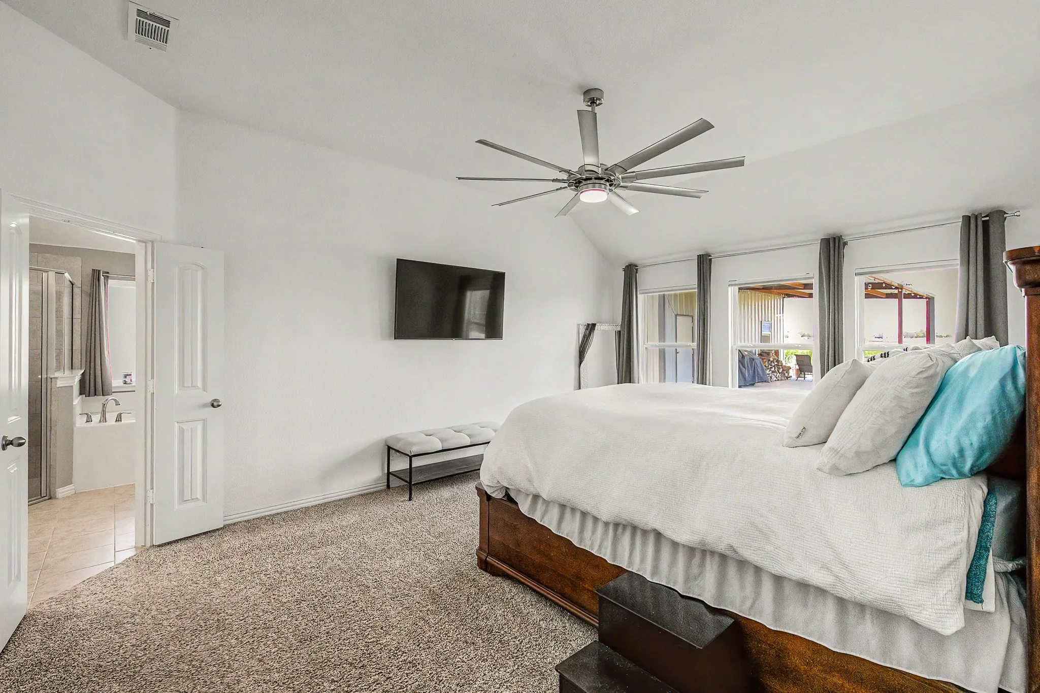 Vaulted ceilings, a contemporary ceiling fan, and multiple windows with exterior access