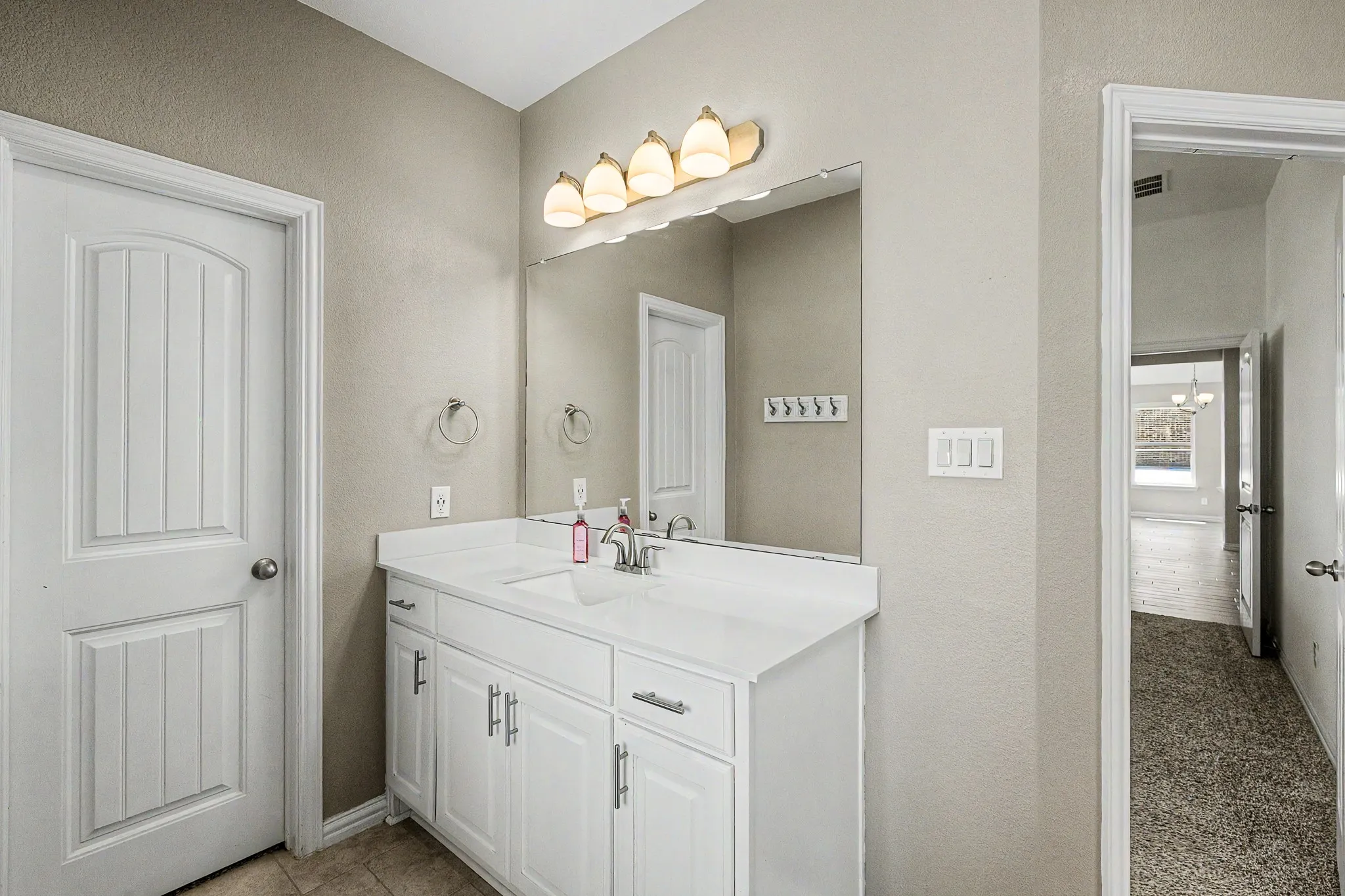 White vanity with integrated sink, polished chrome faucet, and overhead lighting