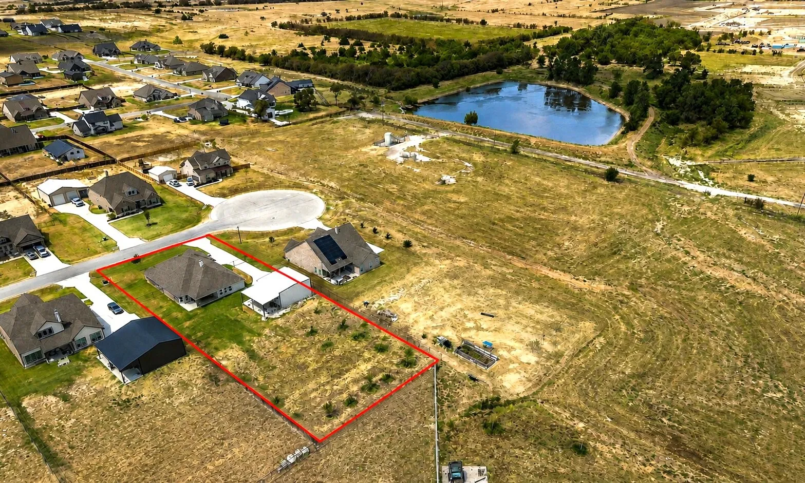 Aerial perspective showcasing a residential area with a prominent body of water, several residential properties, a cul-de-sac, and an open land parcel