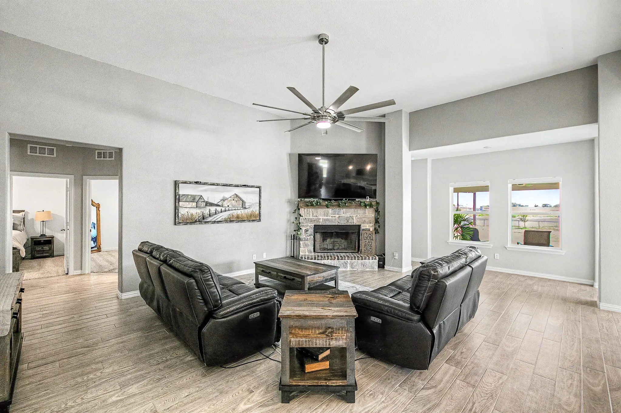 Spacious living area featuring high vaulted ceilings, wood-finish flooring, and a stone-clad fireplace