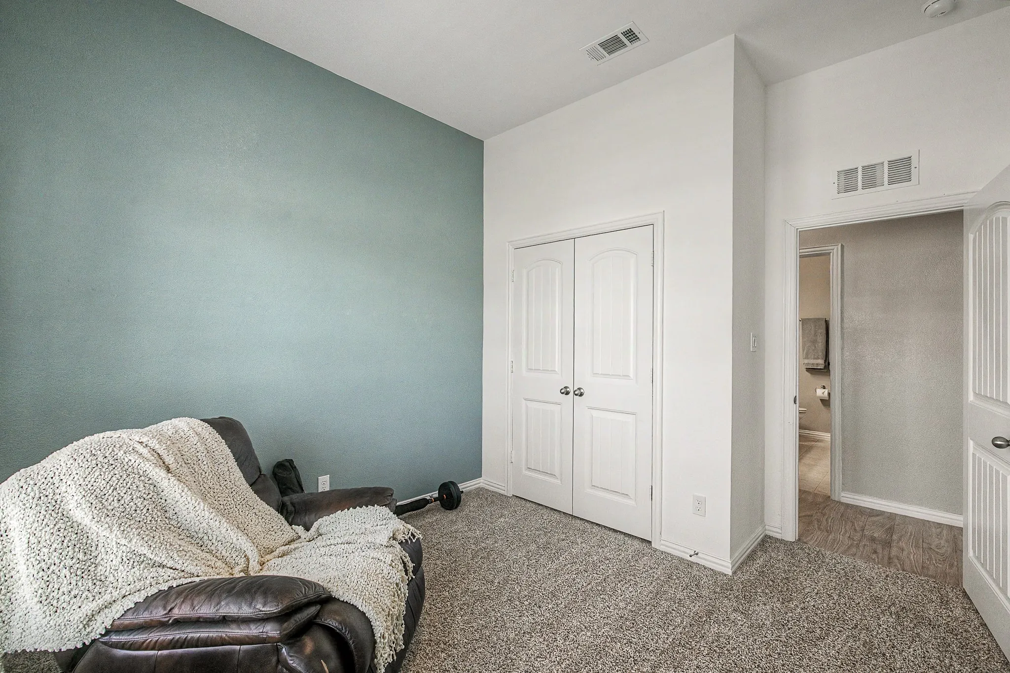 Plush gray carpeting, a textured accent wall, and a white paneled bi-fold door