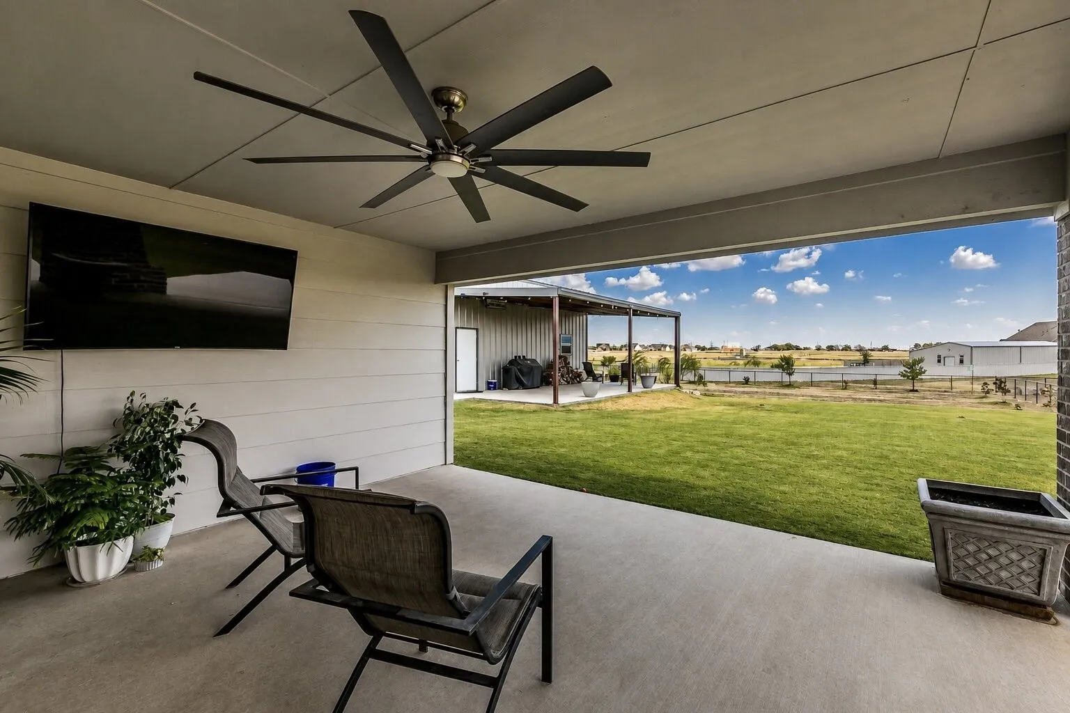 Covered patio with a large ceiling fan and concrete flooring