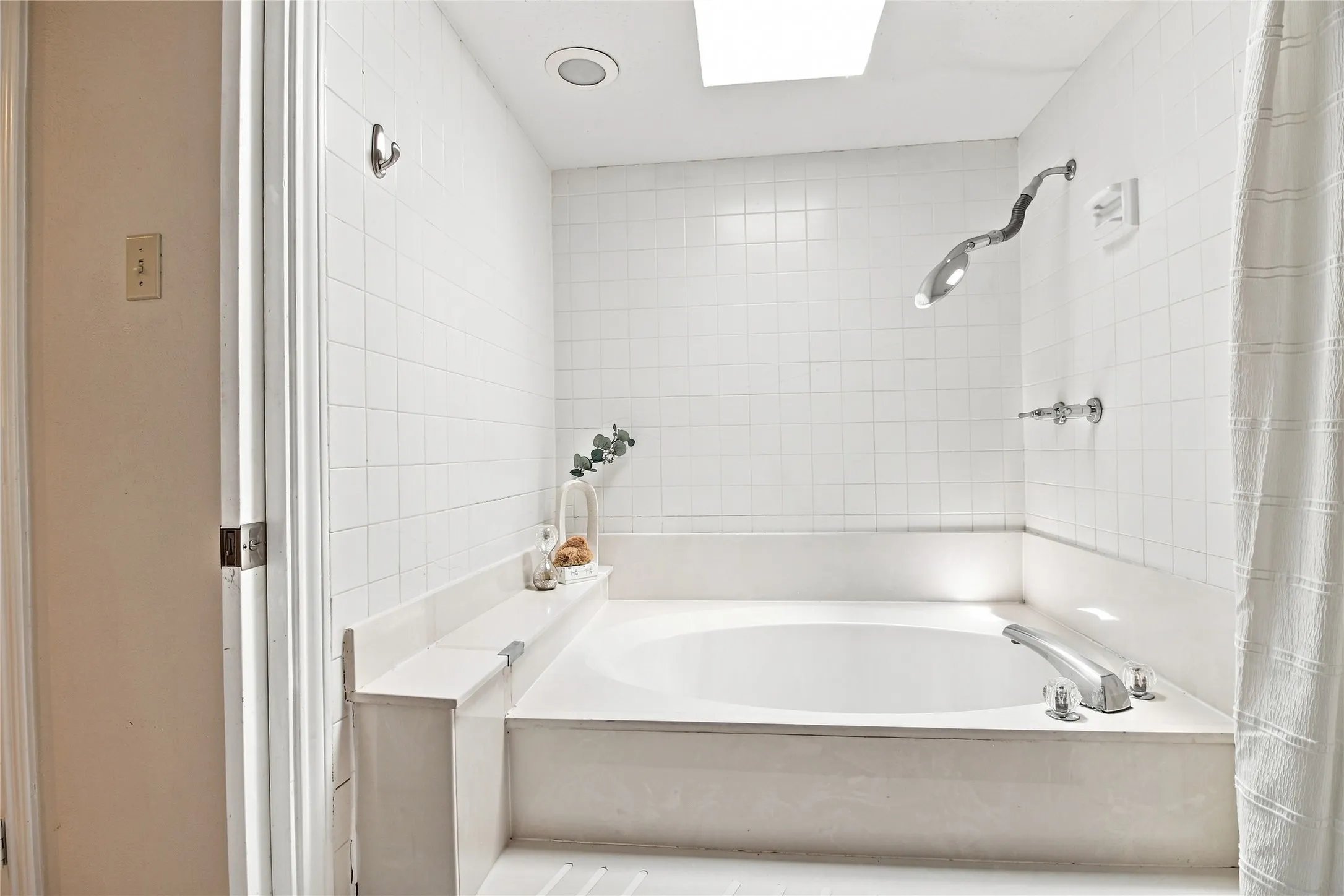 Corner soaking tub with polished chrome fixtures and a built-in shelf