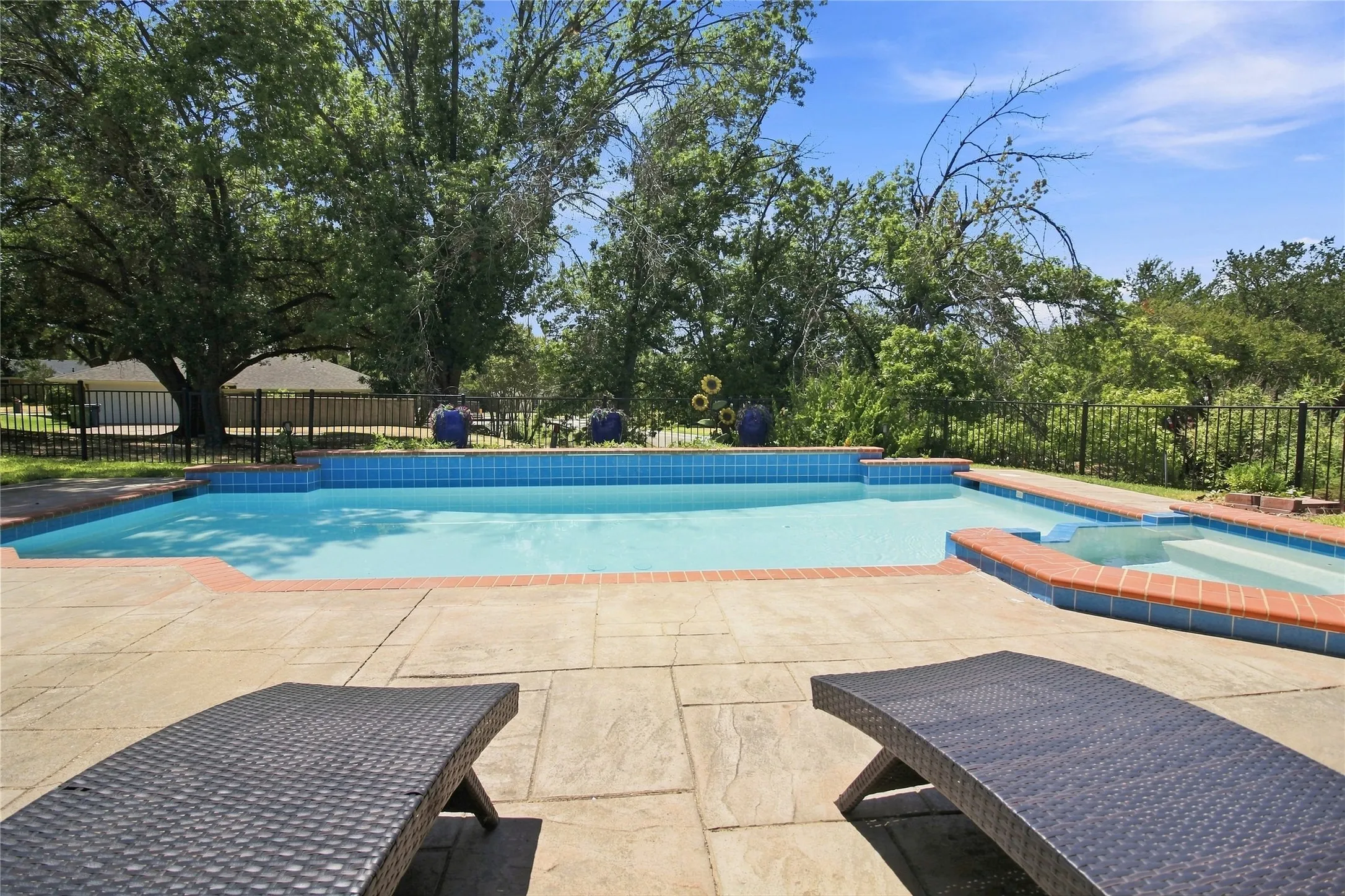 Outdoor swimming pool with integrated spa, surrounded by a stone paver patio