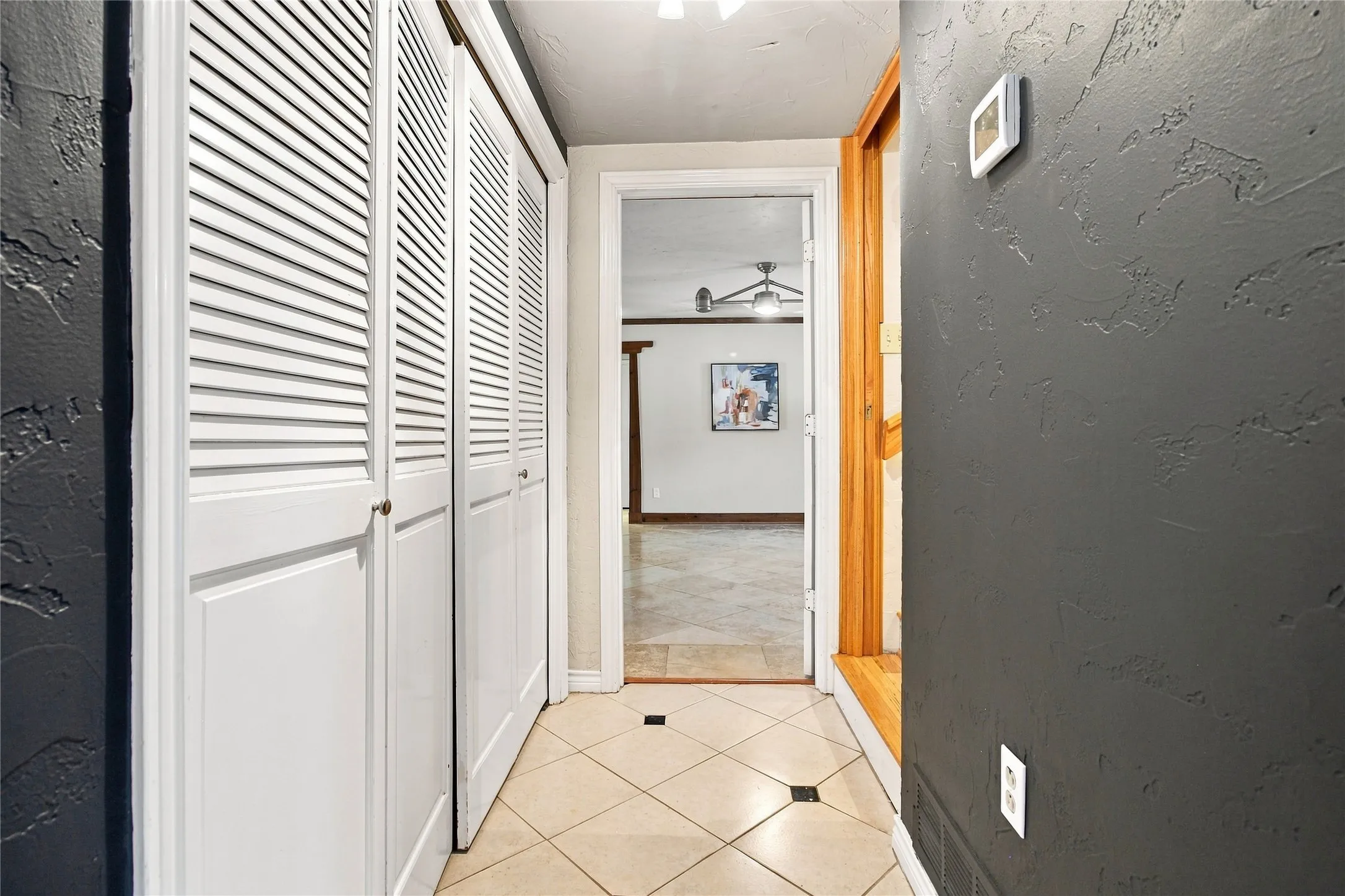 Textured wall finish, louvered bi-fold closet doors, tile flooring with decorative inserts, wood door trim, and recessed lighting