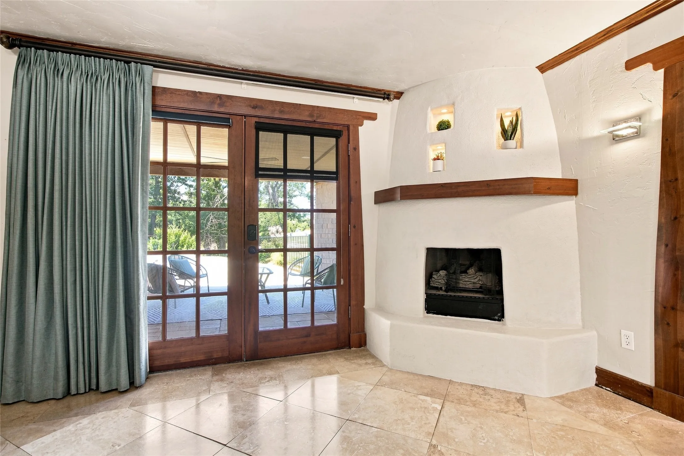 Primary bedroom with tile flooring, built-in fireplace, exposed wood trim, recessed wall niches, and dual ceiling fans with integrated lighting