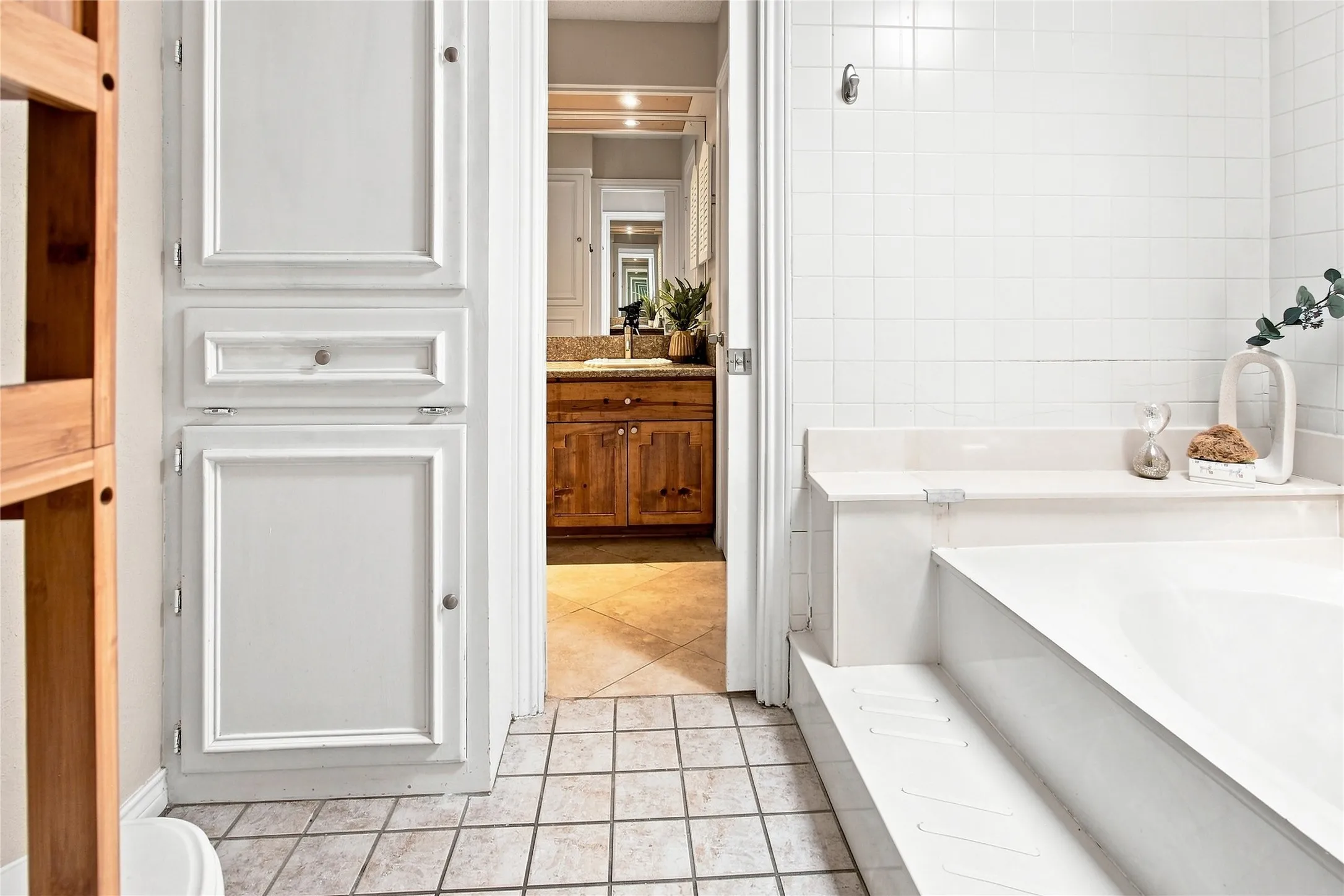 Primary bathroom with built-in cabinetry, ceramic tile flooring, and integrated bathtub with steps