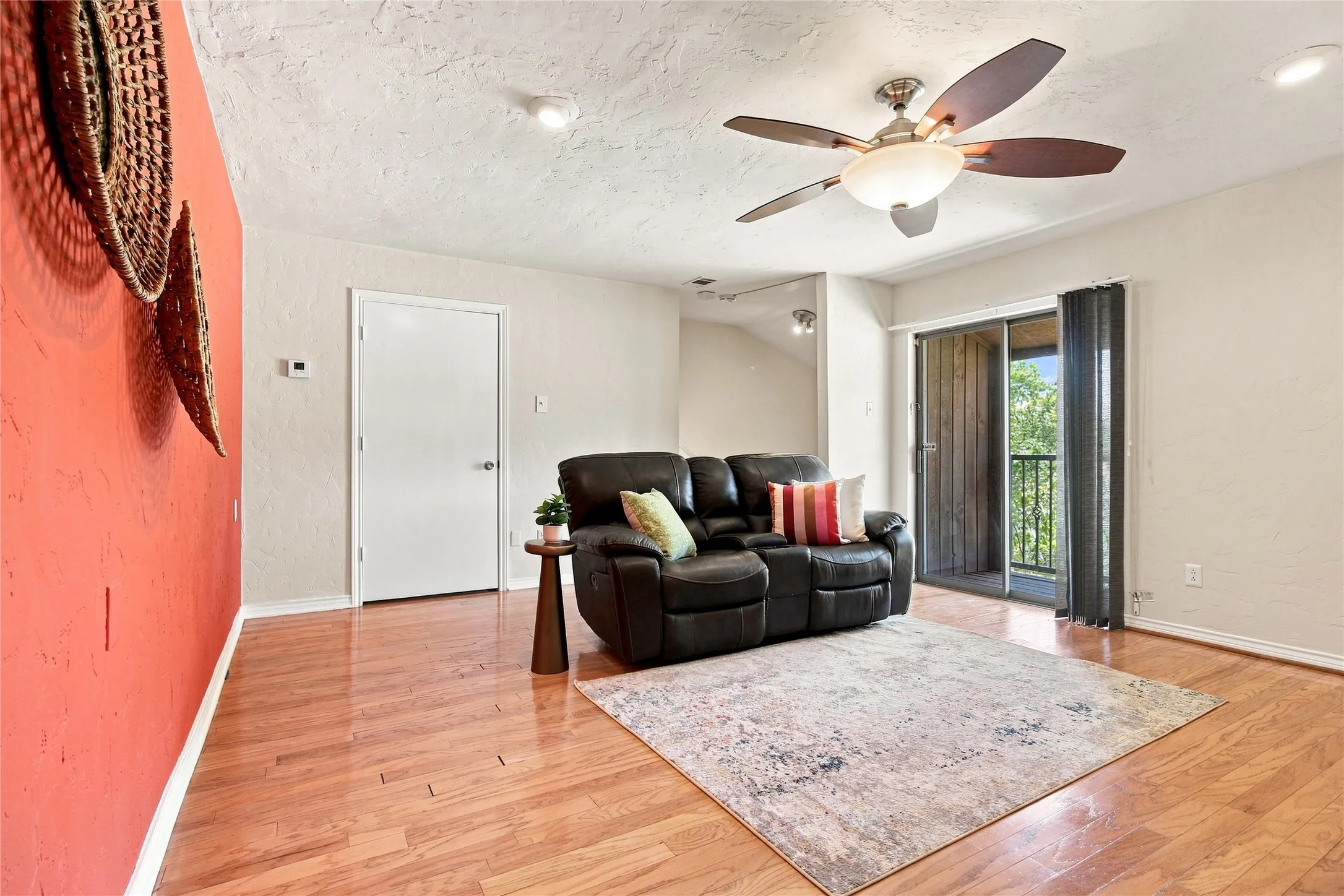 Hardwood-finish flooring, ceiling fan with integrated lighting, sliding glass door with balcony, textured walls, and recessed lighting