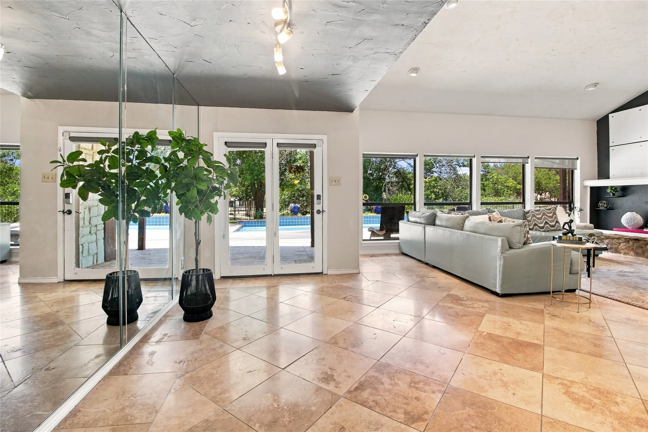 Living room with tile floors, mirrored wall, and stone fireplace