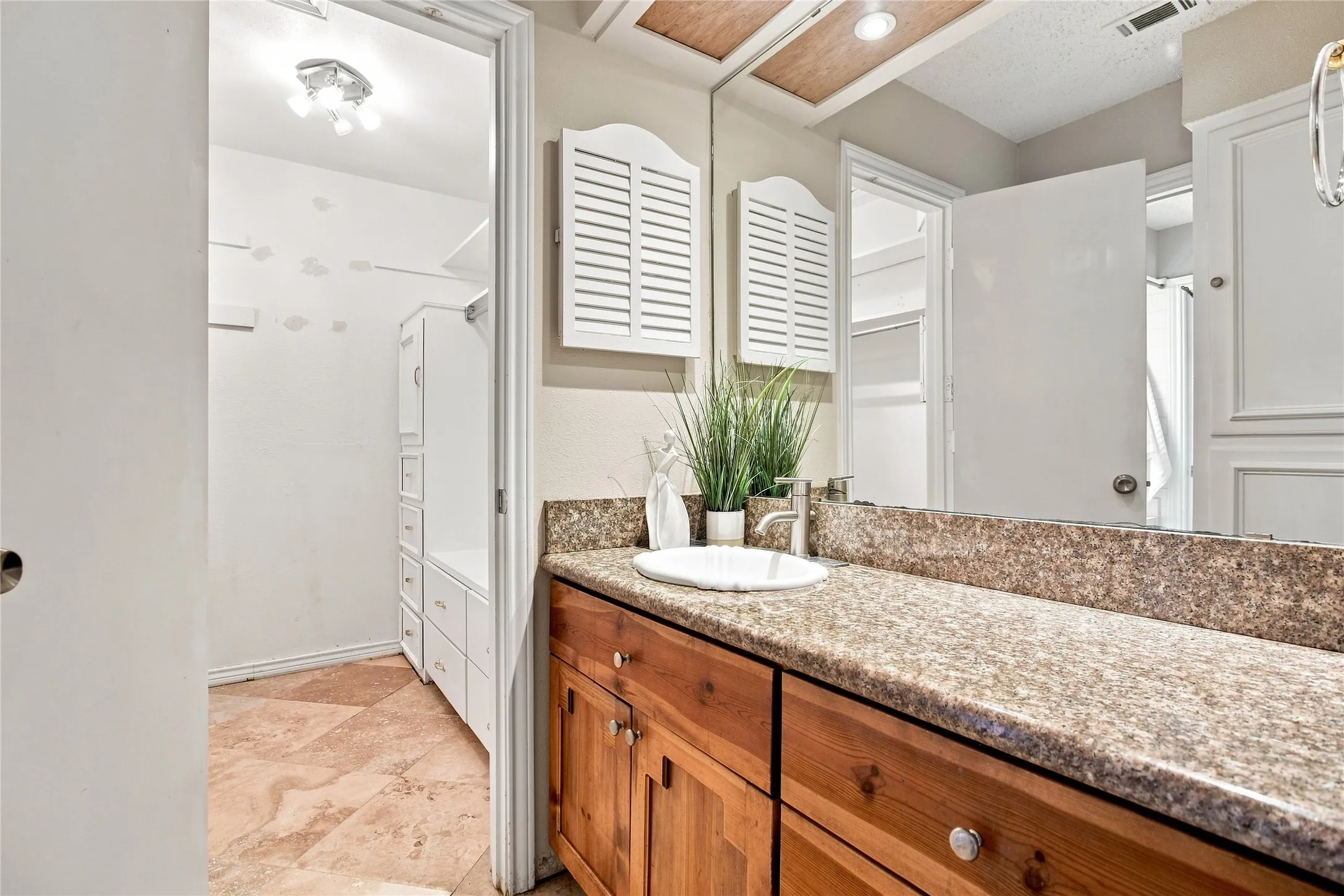 Vanity with a single basin, wood cabinetry, and a stone-finish countertop