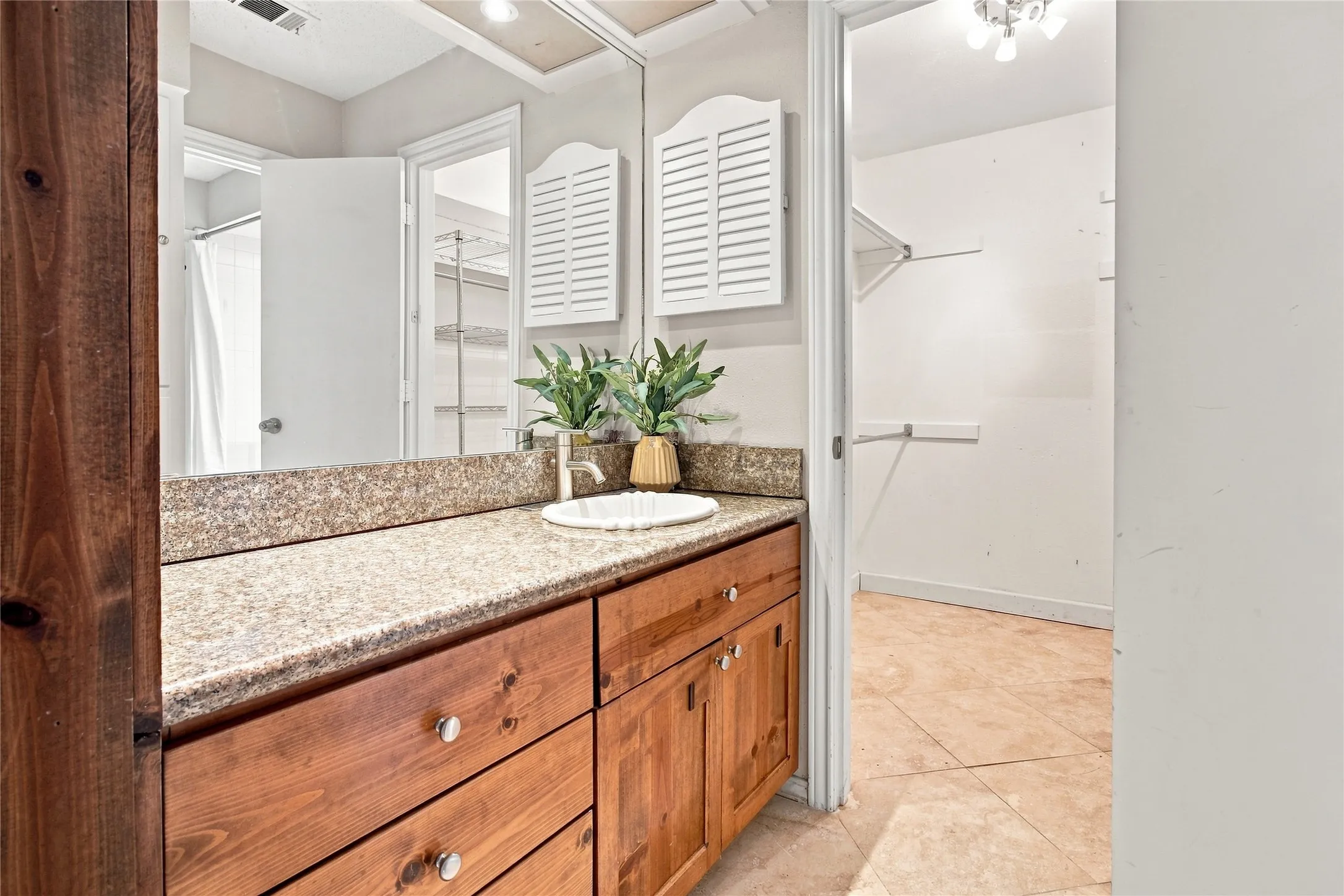 Primary bathroom with a granite-style countertop, undermount sink, and wood-finish cabinetry