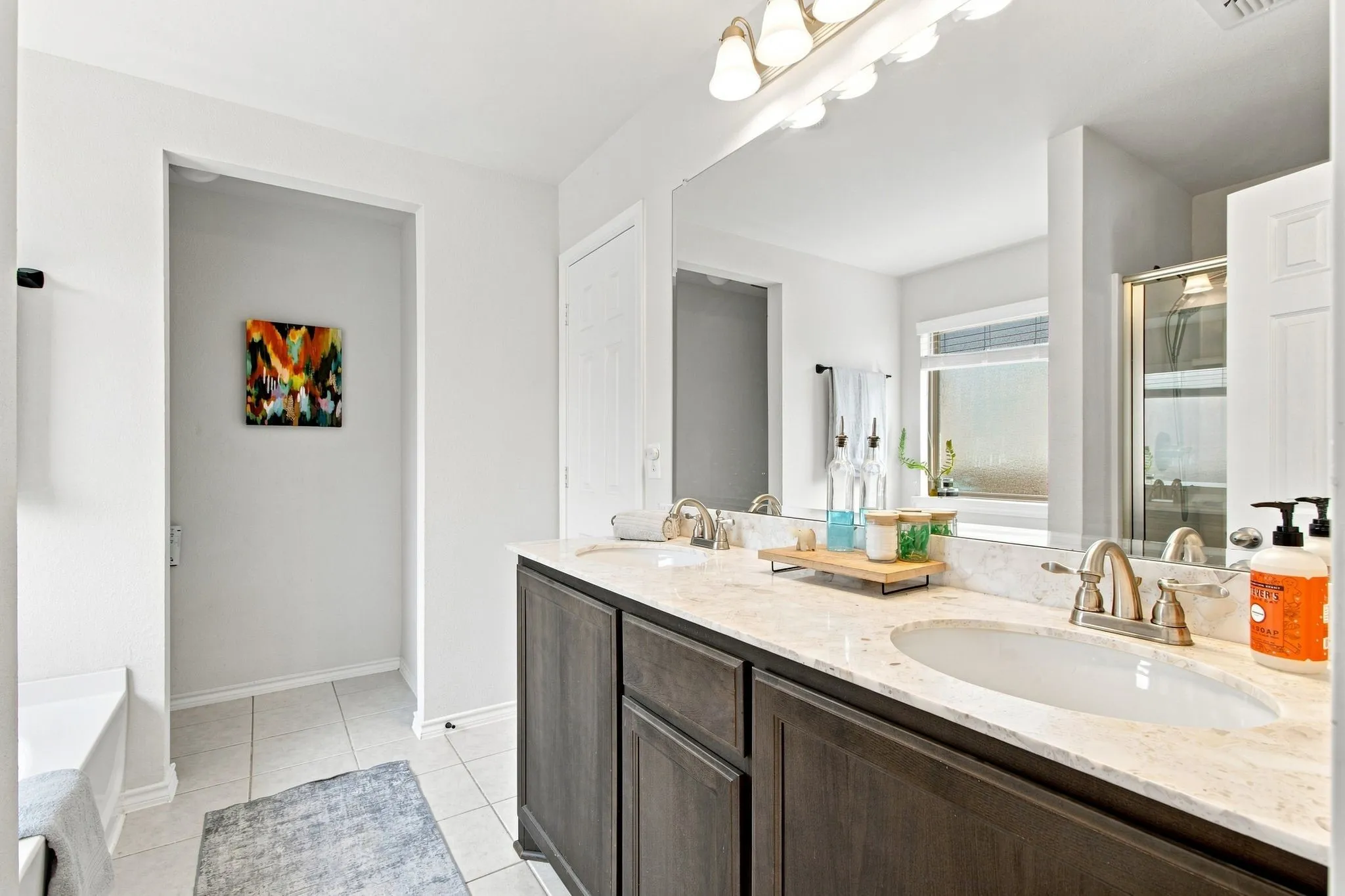 Dual vanity with undermount sinks, stone countertop, and wood-finish cabinetry and on trend nickel finish lighting and faucets