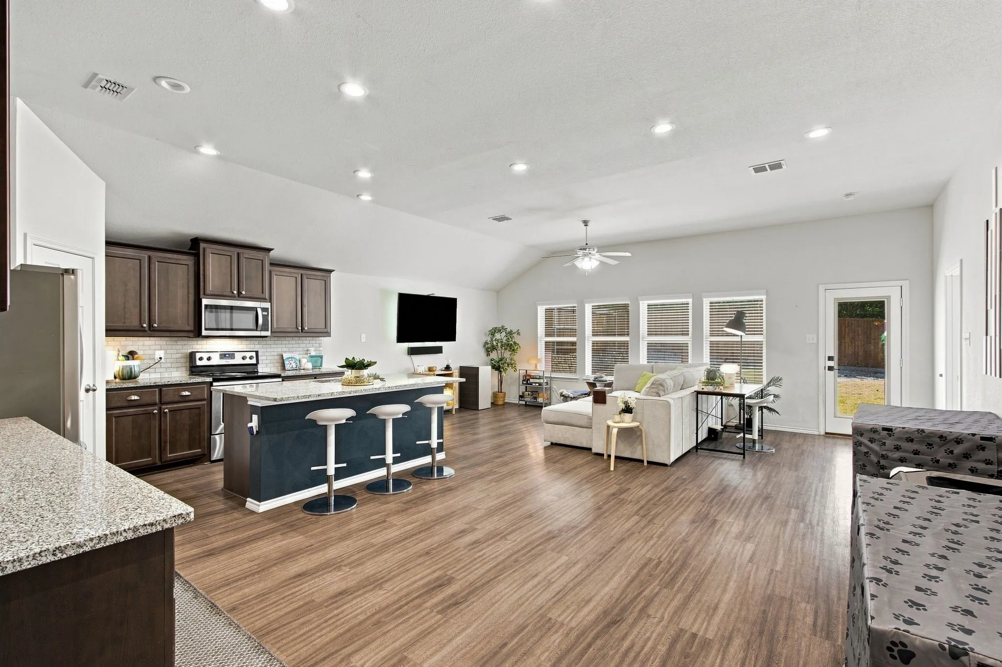 Open-concept living area with wood-finish LVP flooring, a vaulted ceiling, and recessed lighting