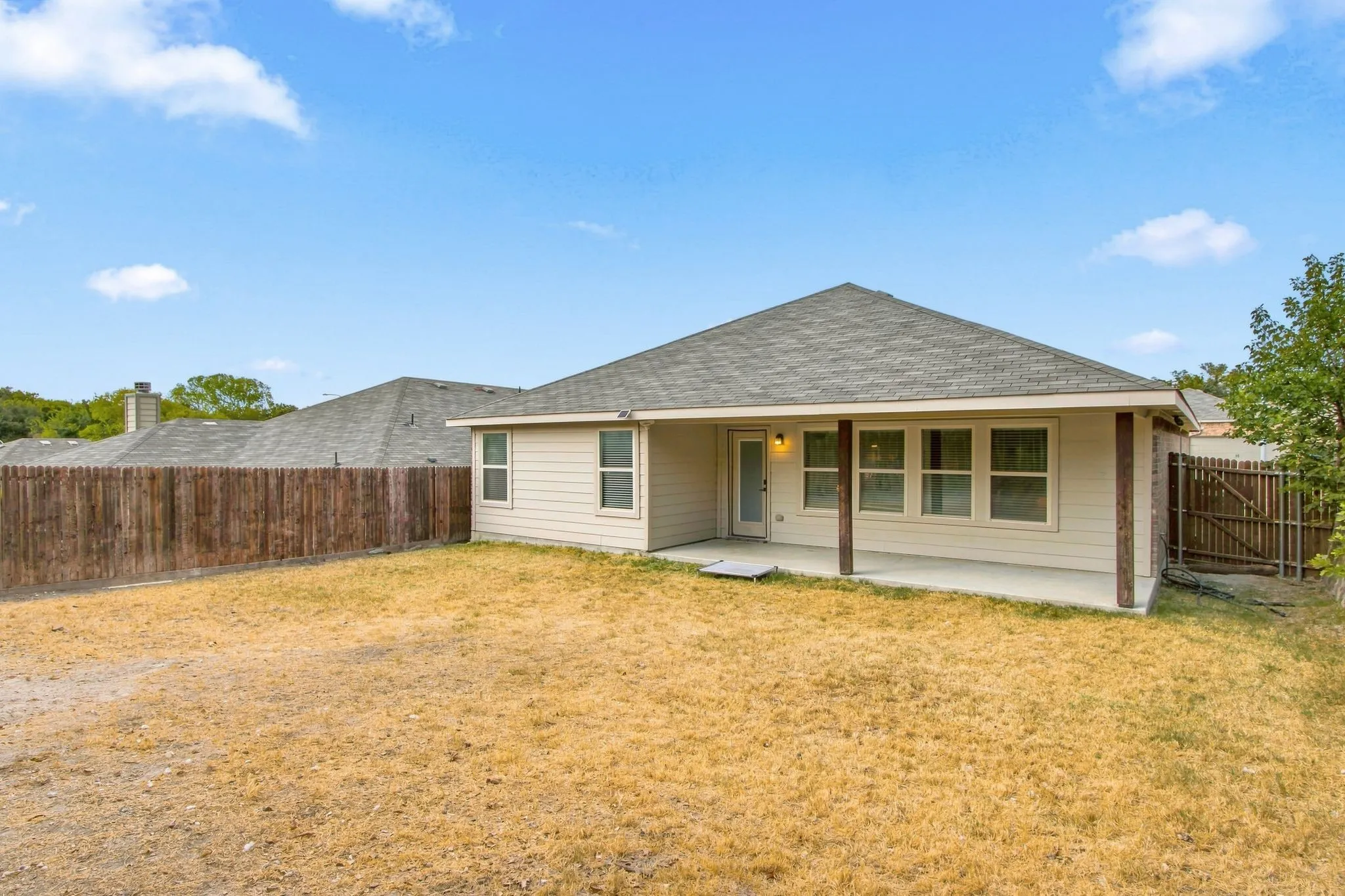 Rear exterior with covered patio, wood posts, and a full wood privacy fence