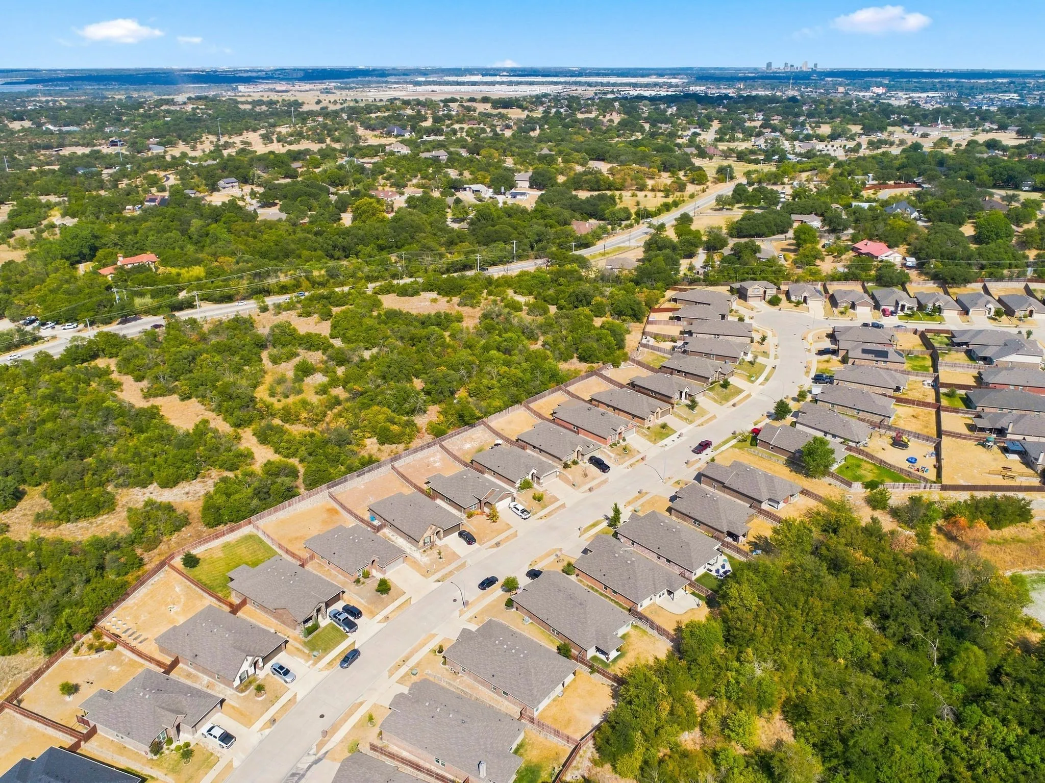New residential development featuring single-family homes and paved streets, surrounded by natural landscaping and mature trees