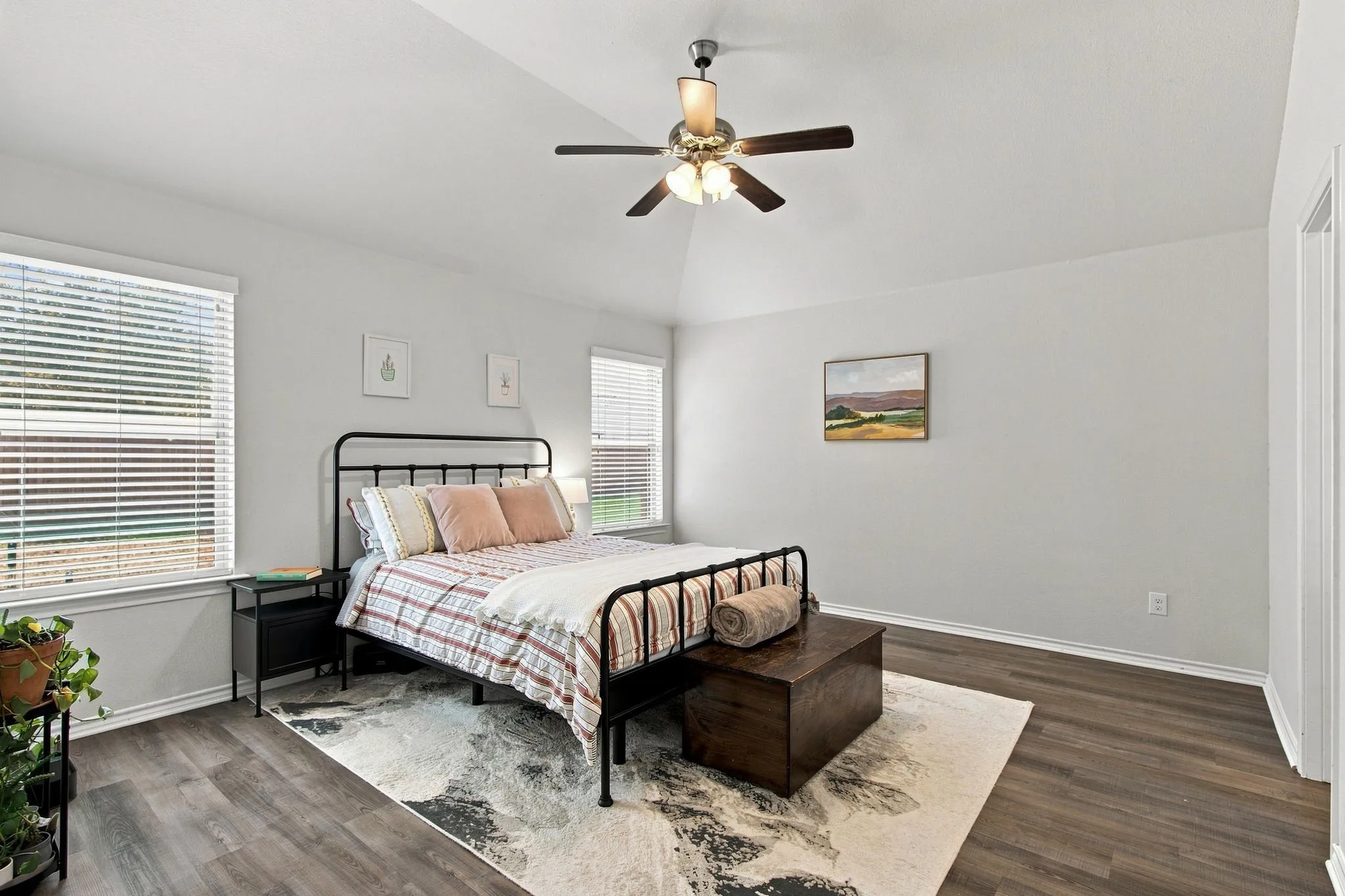 Vaulted ceiling with a ceiling fan, wood-finish LVP flooring, and multiple windows