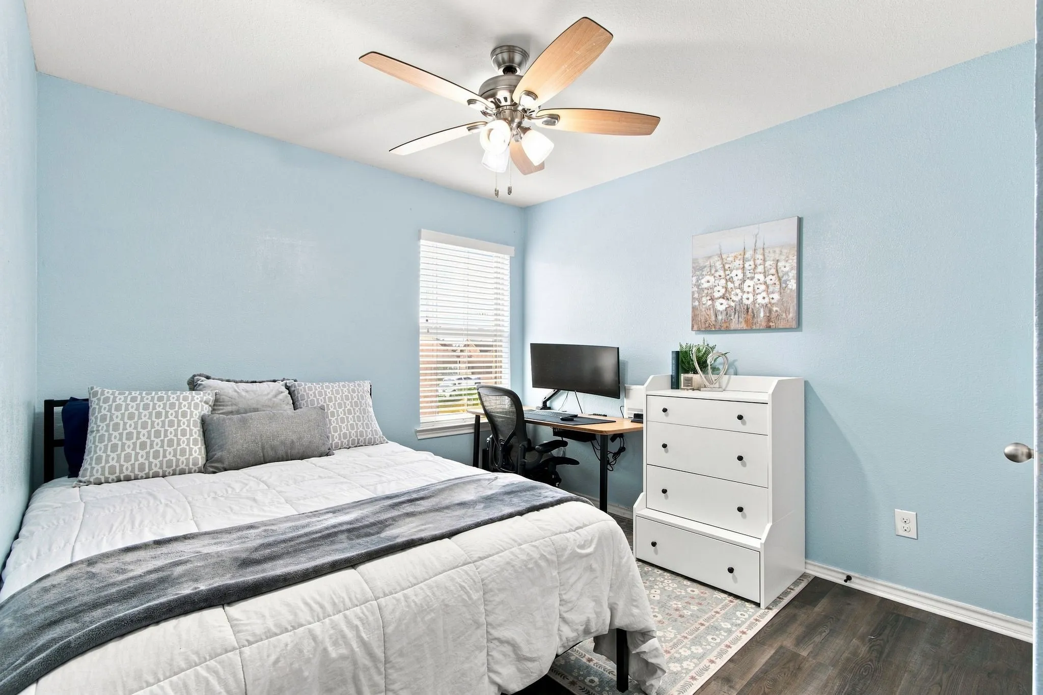 Wood-finish LVP flooring, ceiling fan with integrated lighting, window with blinds, and light blue wall finishes. Bedroom 2