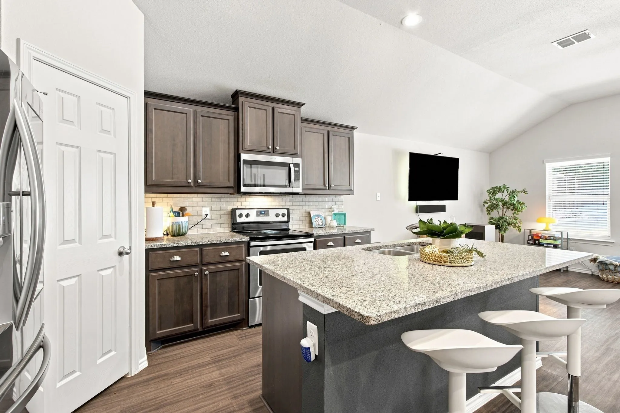 Kitchen featuring and on trend granite island &  countertops, stainless steel appliances, and a walk in pantry