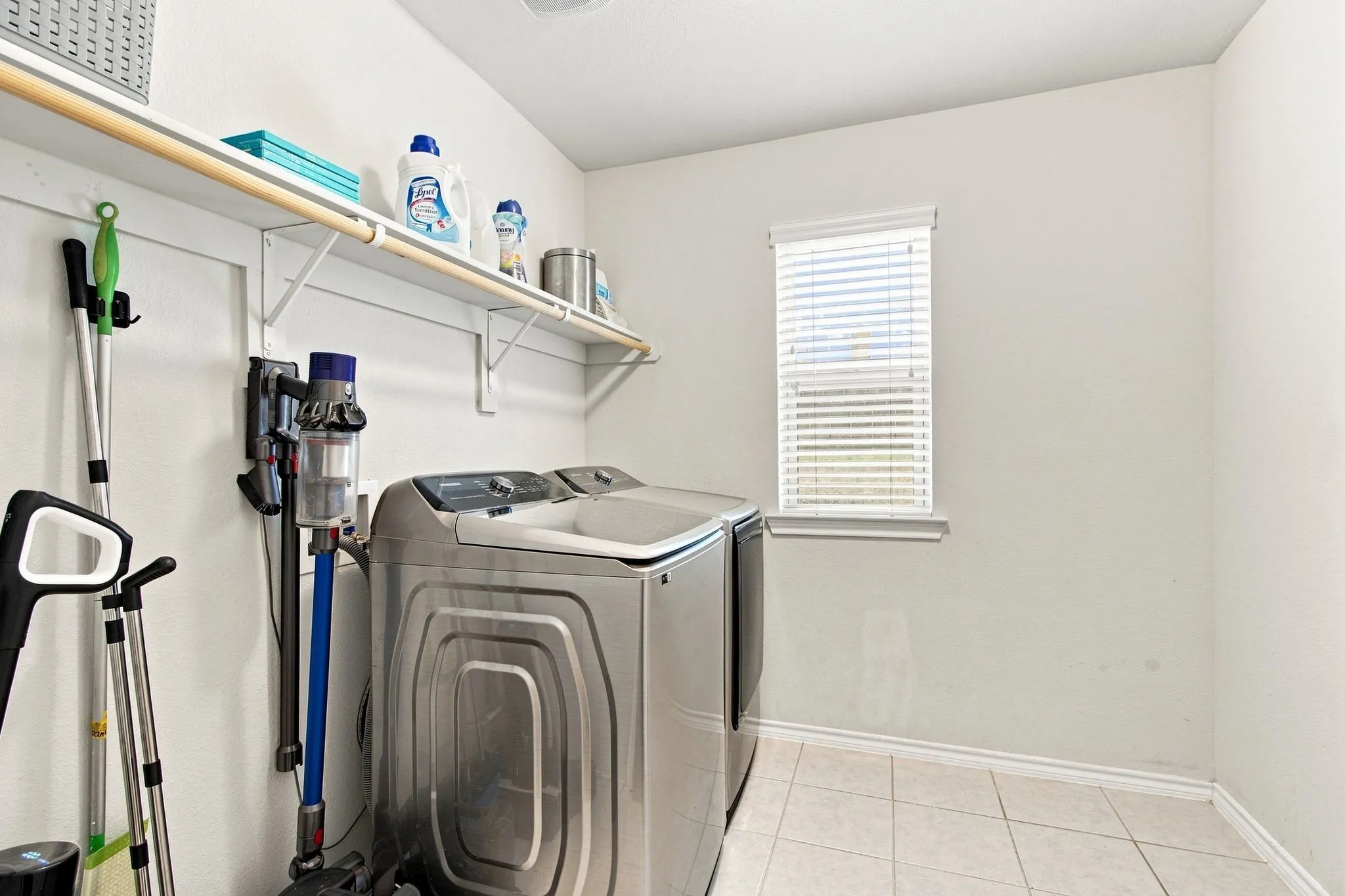 Laundry room with ceramic tile flooring, upper shelving, and a single window. Room for a second refrigerator