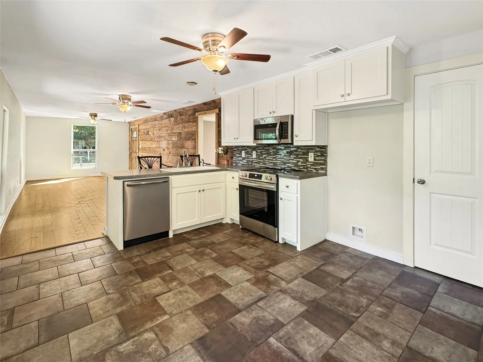 Kitchen featuring white cabinetry, stainless steel appliances, and a mosaic tile backsplash