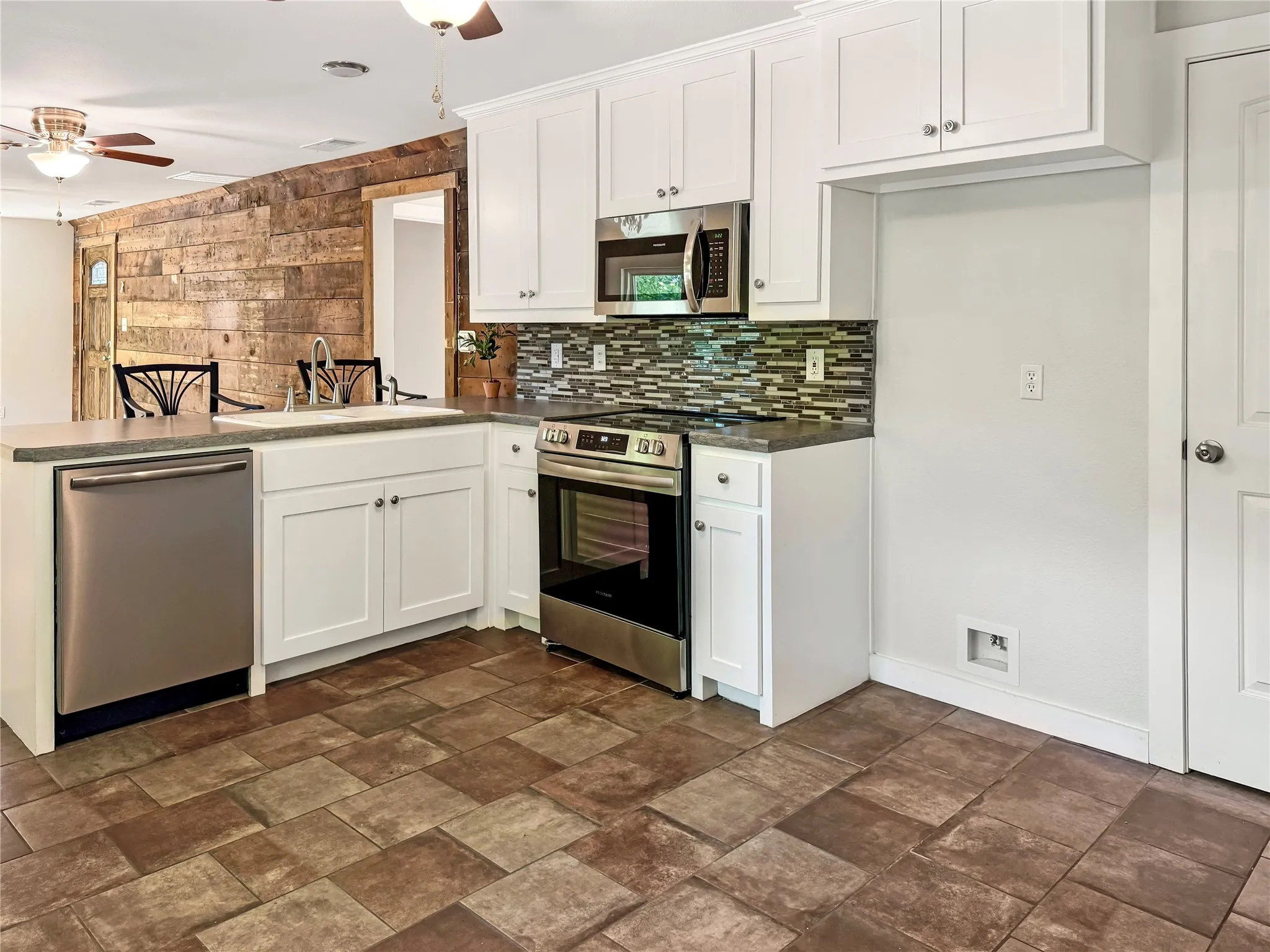 White cabinetry, stainless steel appliances, patterned tile backsplash