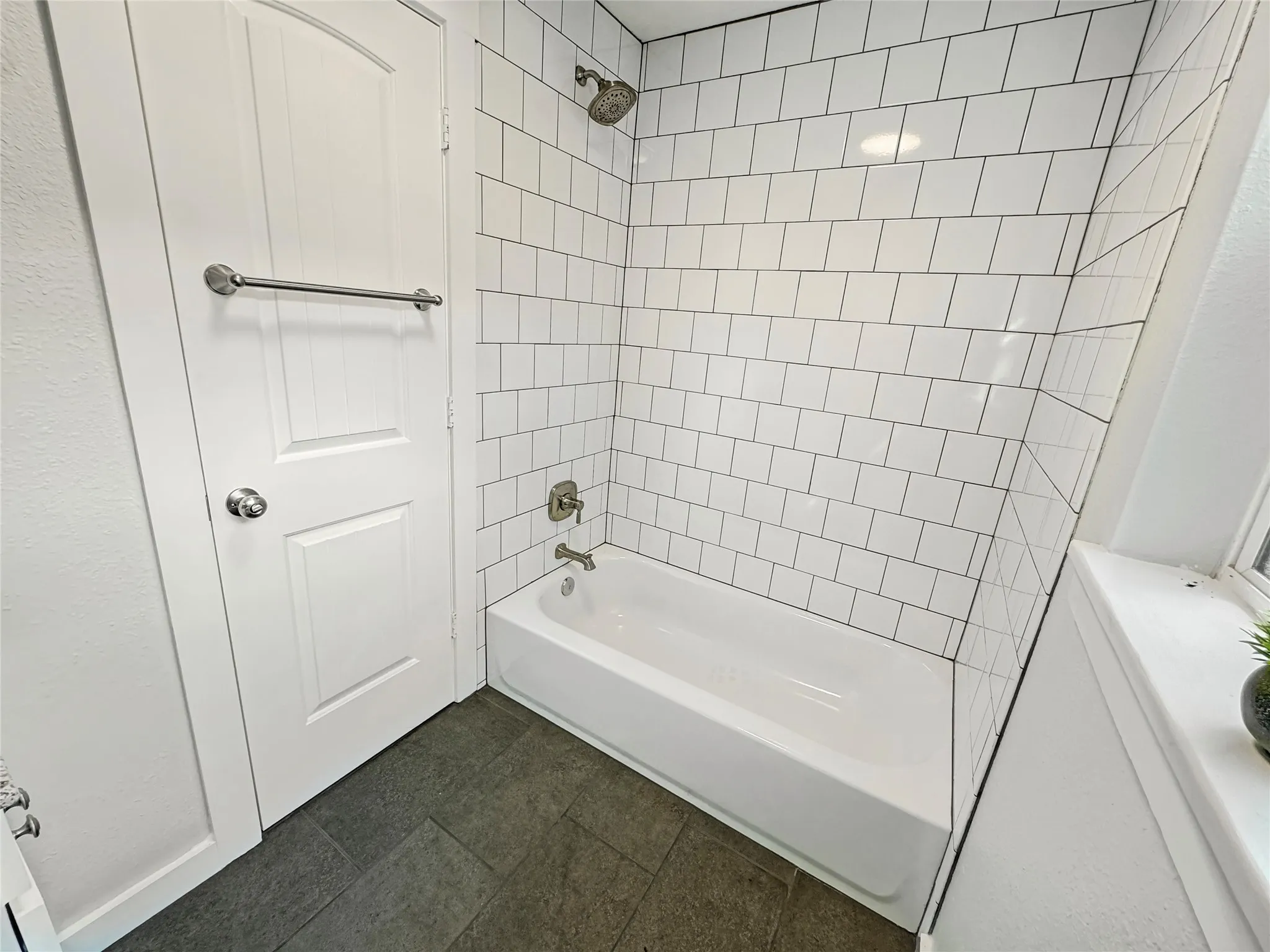 Hallway Bathroom - Bathtub with subway tile surround, brushed nickel fixtures, and dark floor tiles