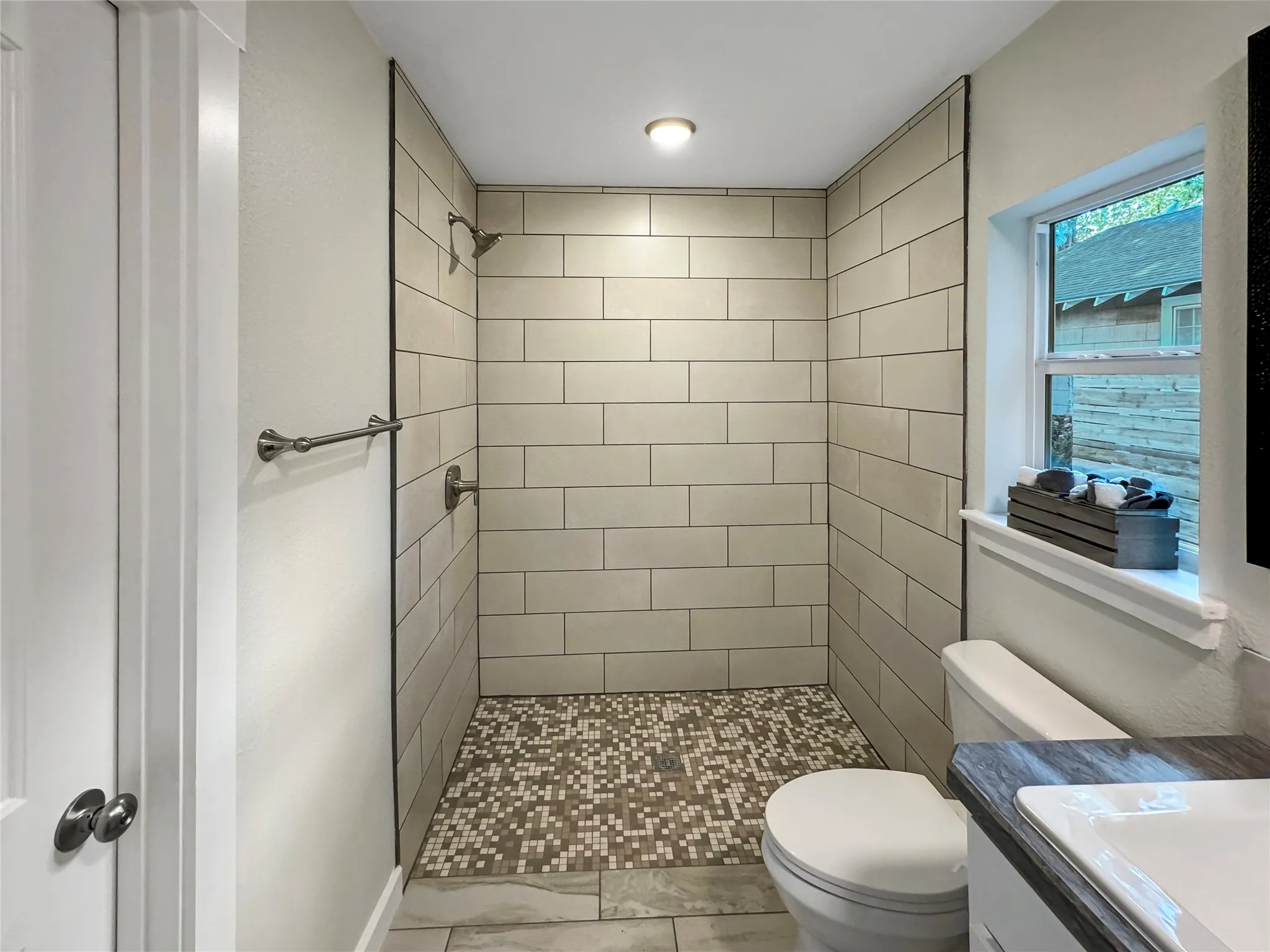 Walk-in shower with subway tile surround and mosaic tile floor - wheelchair accessible