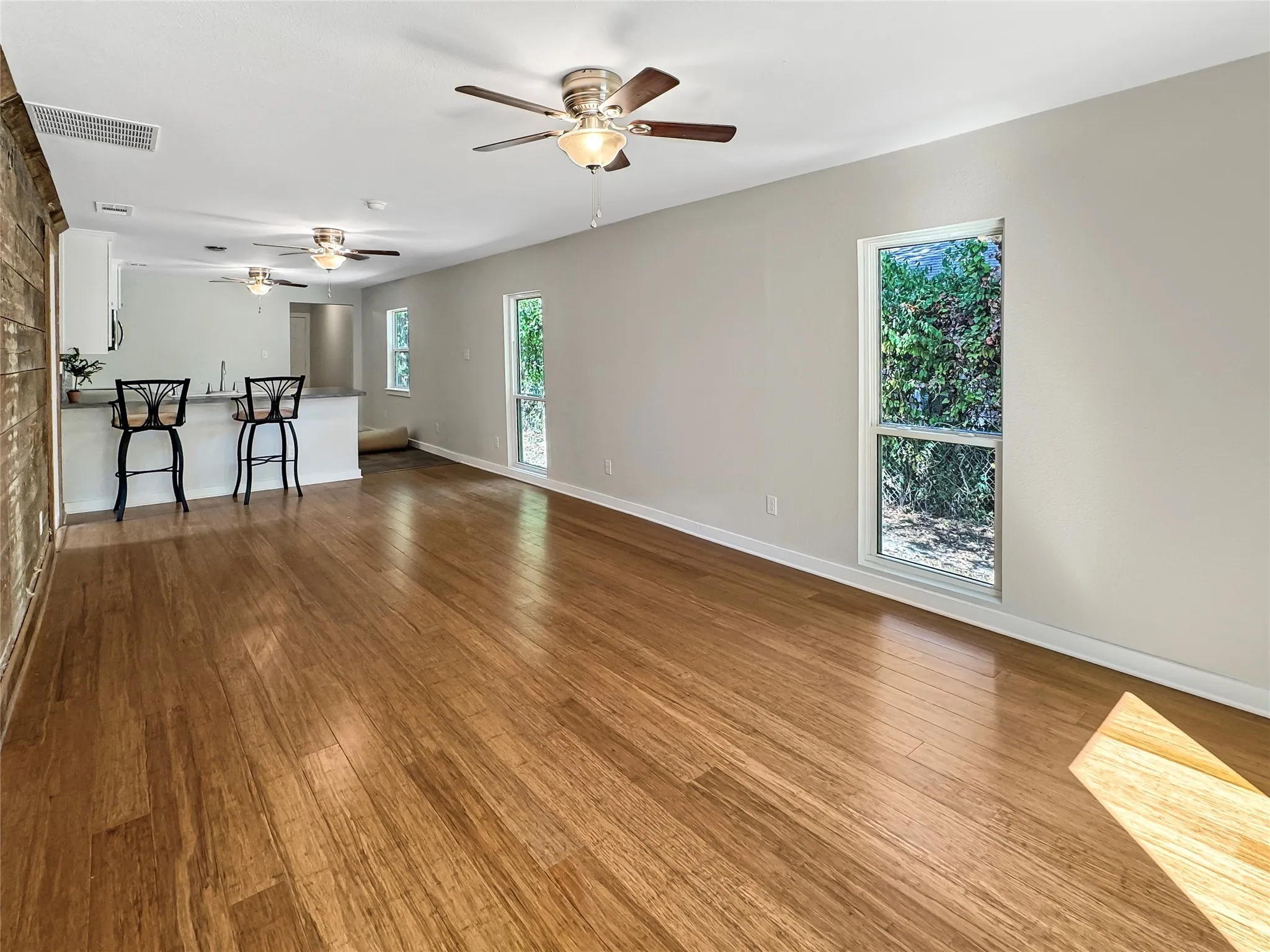Open-concept living area with Bamboo flooring, white walls, and multiple windows