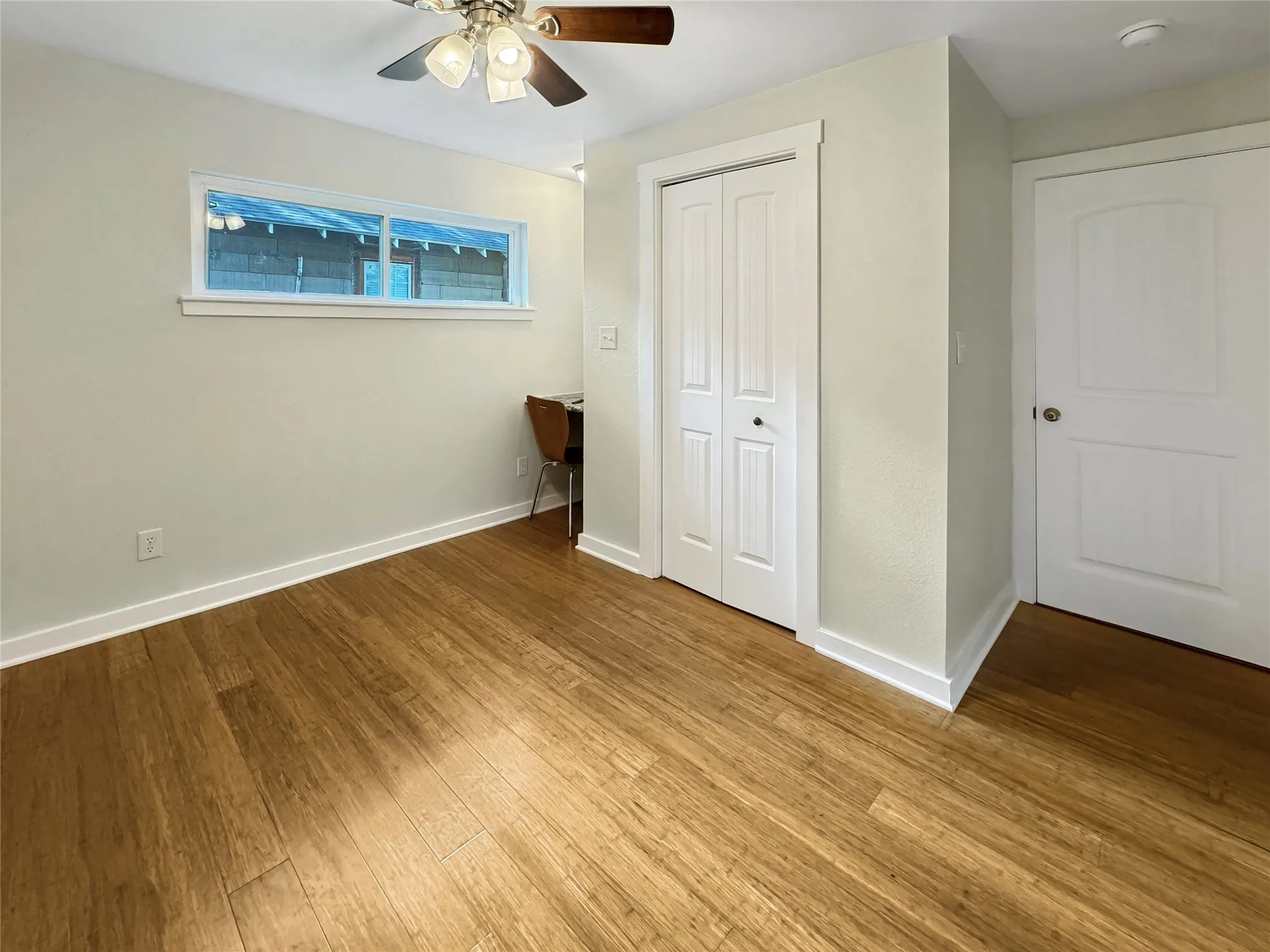 Secondary Bedroom - Bamboo flooring, ceiling fan with light fixture, horizontal window, and white interior doors