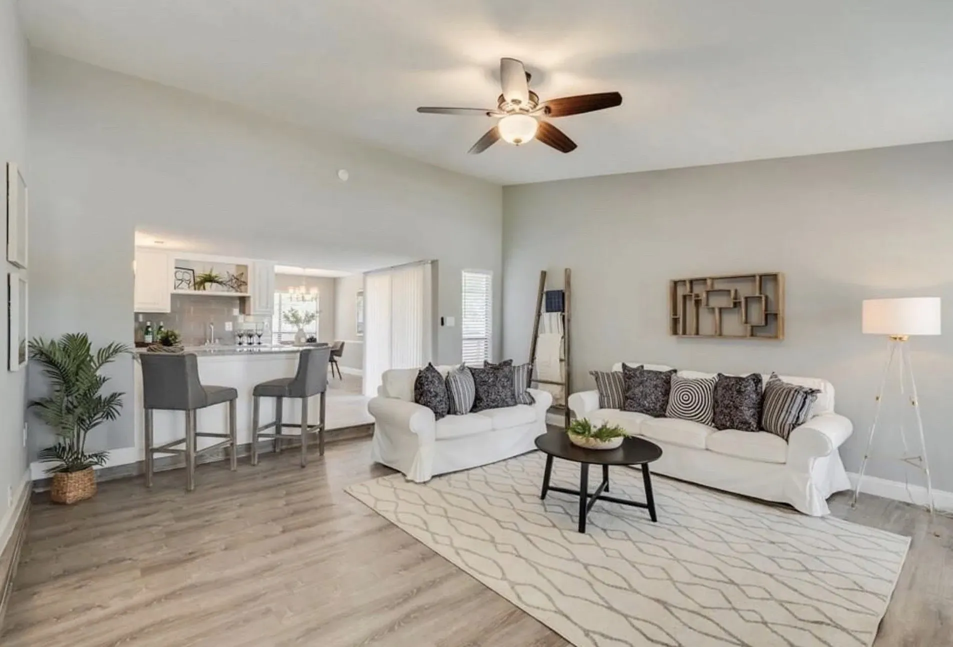 Vaulted ceiling with a ceiling fan, wood-finish flooring, and a kitchen pass-through with a breakfast bar