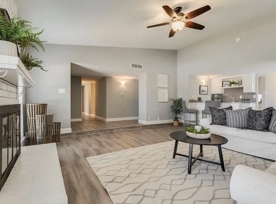 Vaulted ceilings, wood-finish flooring, white fireplace with subway tile surround, recessed lighting, and a ceiling fan