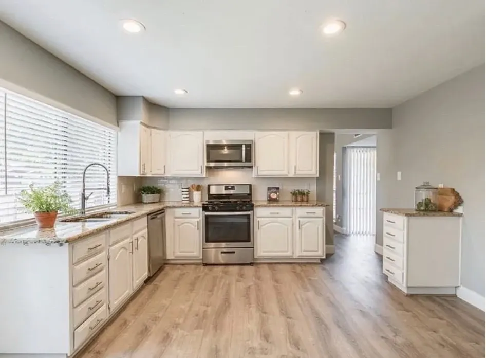 Kitchen featuring wood-finish flooring, white cabinetry, a tiled backsplash, and stainless steel appliances