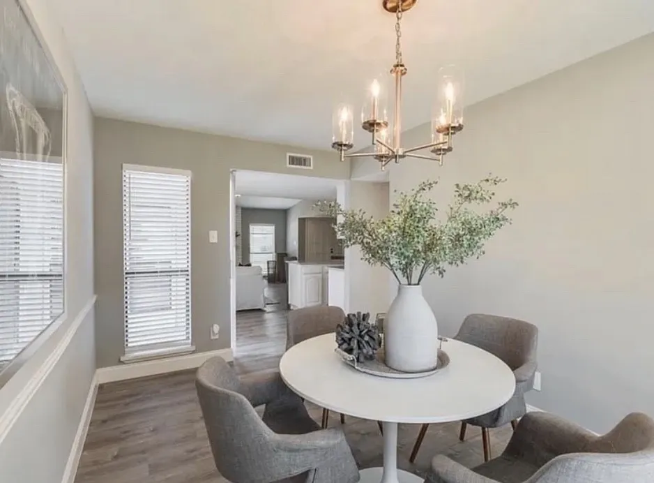 Recessed window with horizontal blinds, wood-finish flooring, and a contemporary chandelier with glass shades