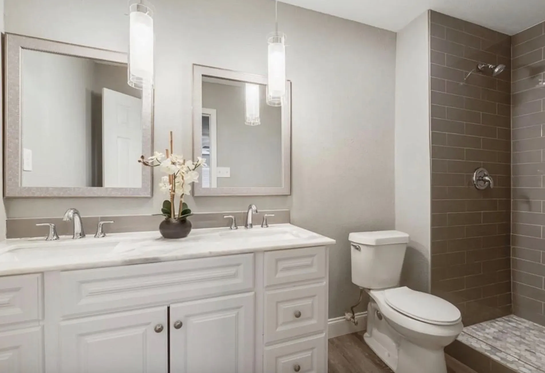 Dual vanity with framed mirrors, polished chrome fixtures, and white cabinetry