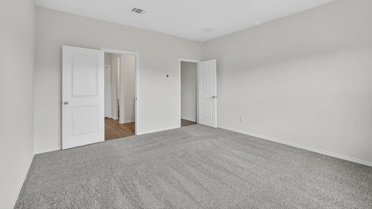 Spacious room featuring light gray walls, gray carpeting, white baseboards, and two-panel interior doors