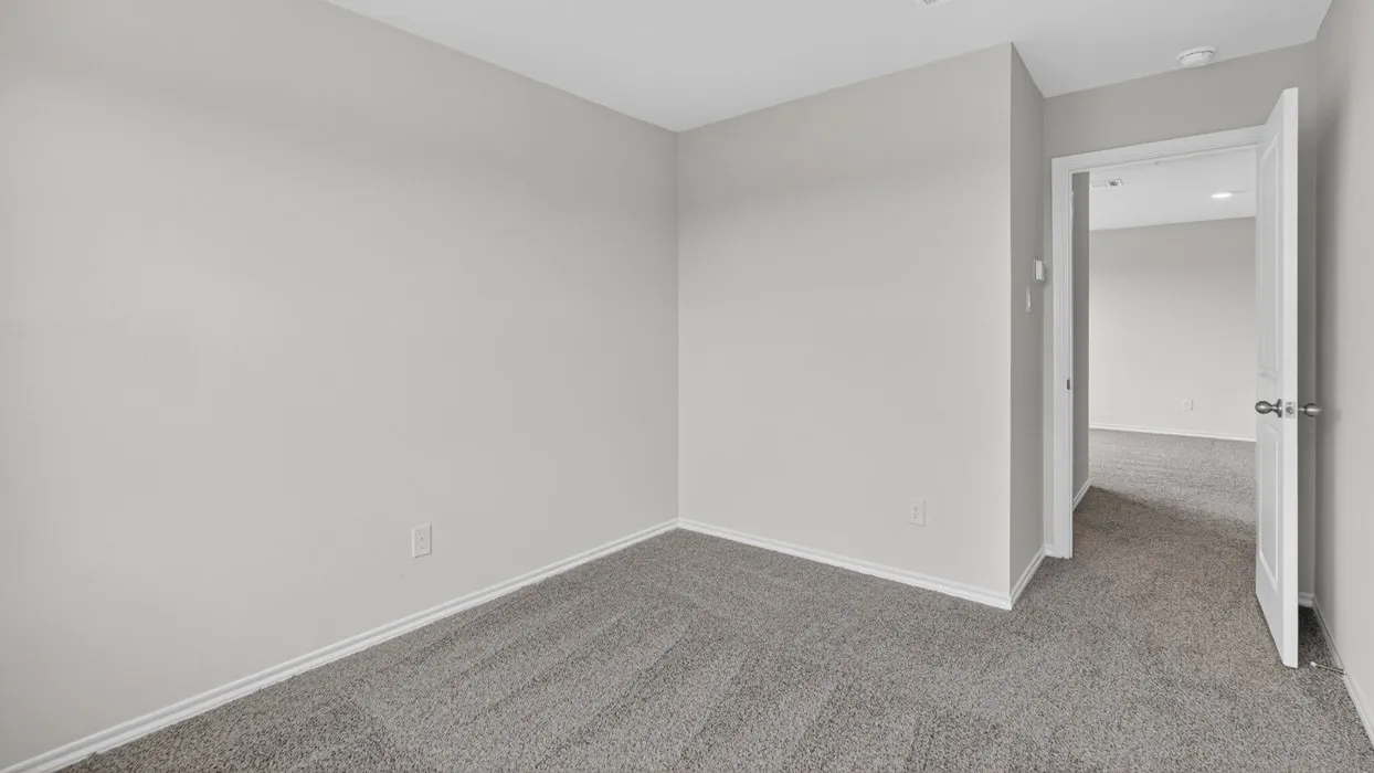 Room featuring light gray wall paint, gray carpeting, white baseboards, and a white interior door with a silver knob