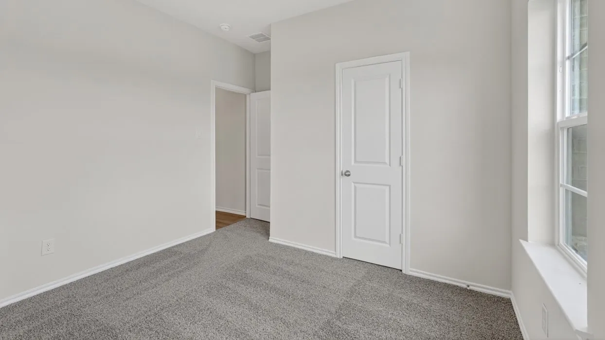 Carpeted interior room featuring light gray walls, white trim, a single window, and a paneled door