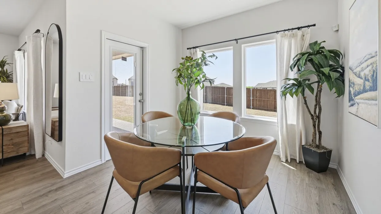 Bright dining area featuring wood-finish flooring, white walls, and a glass-paneled back door