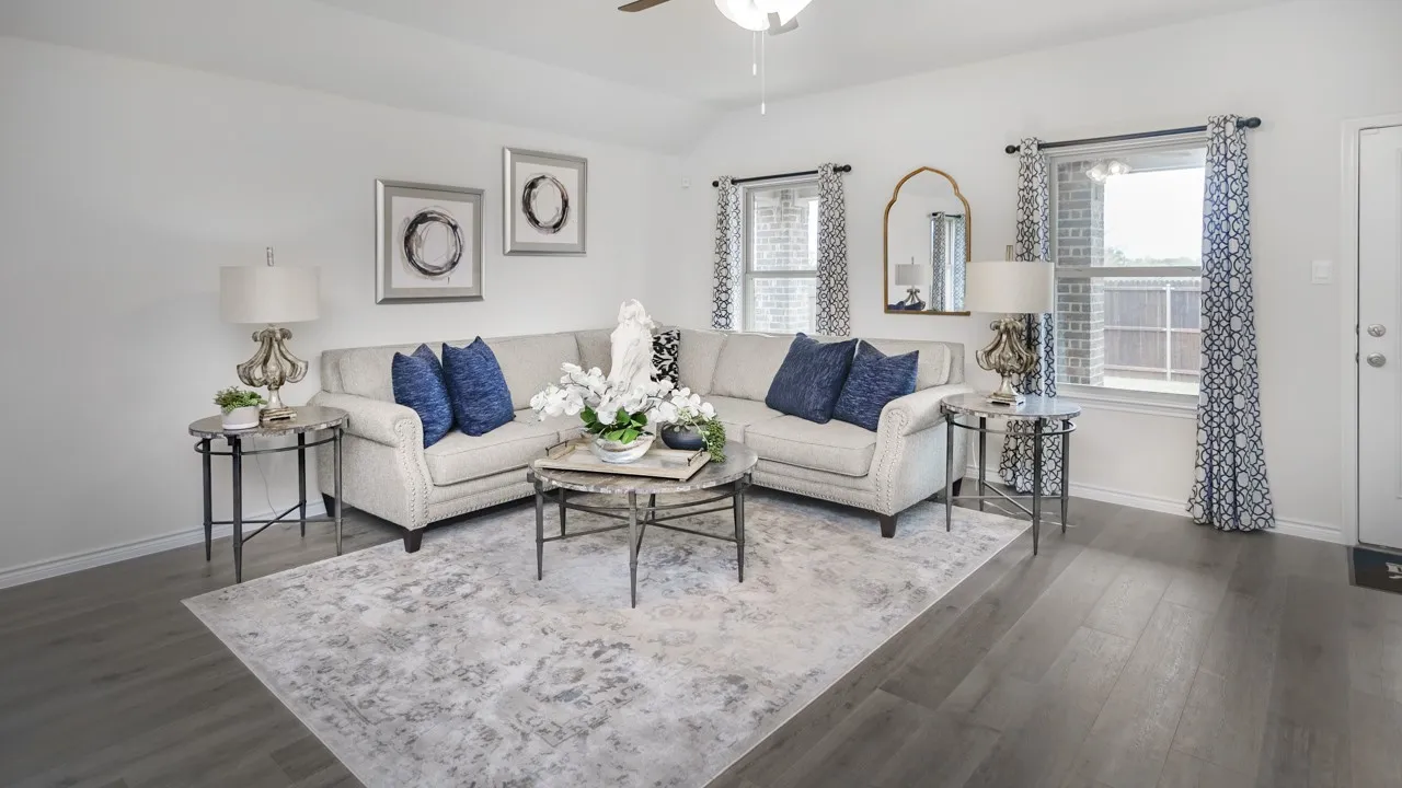 Spacious living area featuring wood-finish flooring, white walls, and multiple windows