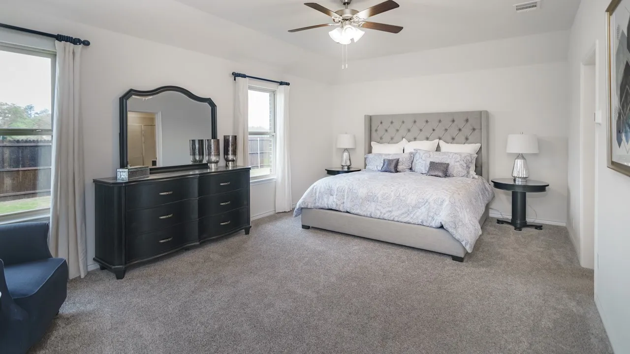 Spacious room with light gray carpeting, neutral wall color, and two windows with white trim